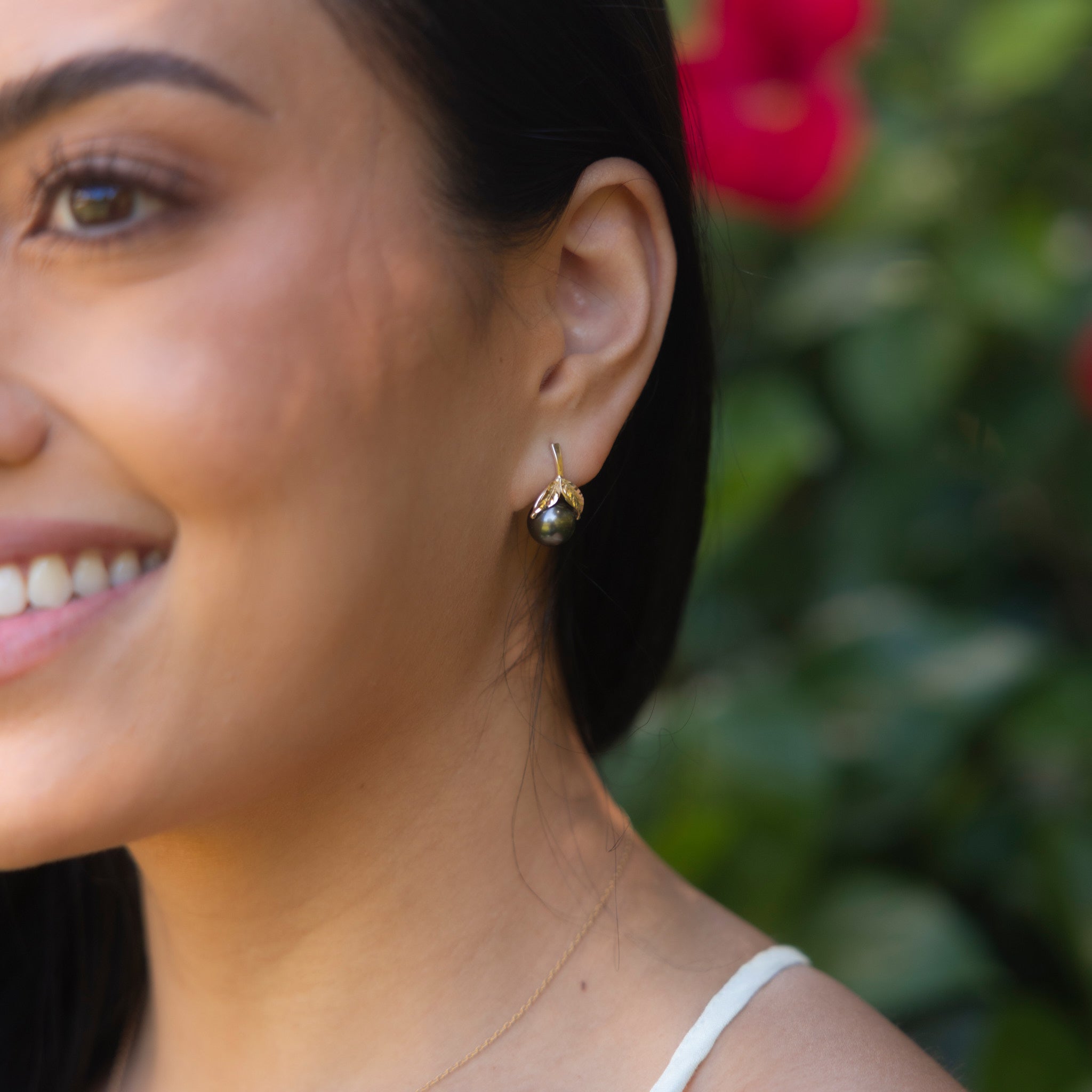 Close up of Maile Tahitian Black Pearl Earrings in Gold on Woman's Ear