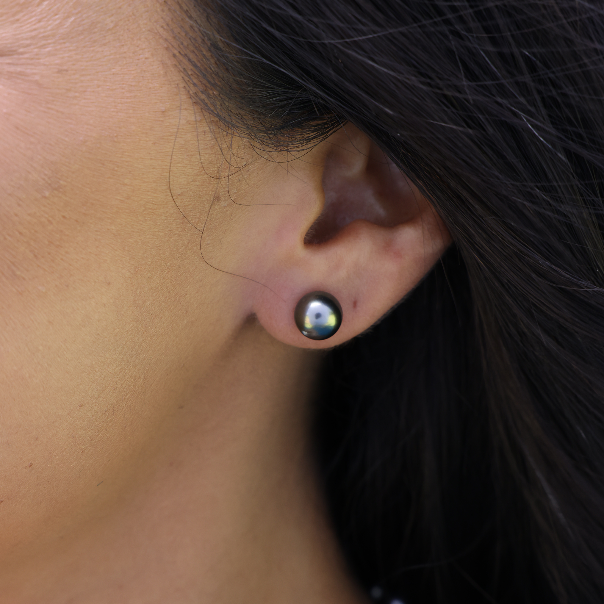 Close up of an ear wearing a Tahitian black pearl stud earring