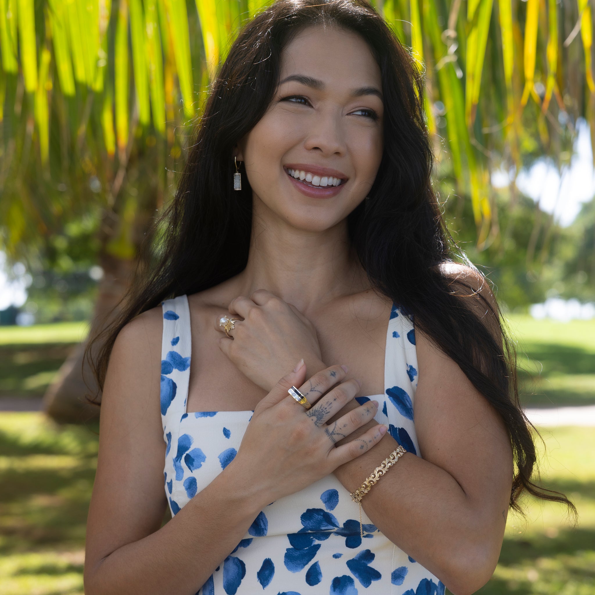Smiling woman in a park wearing a Living Heirloom Hinge Bracelet in 14k Yellow Gold