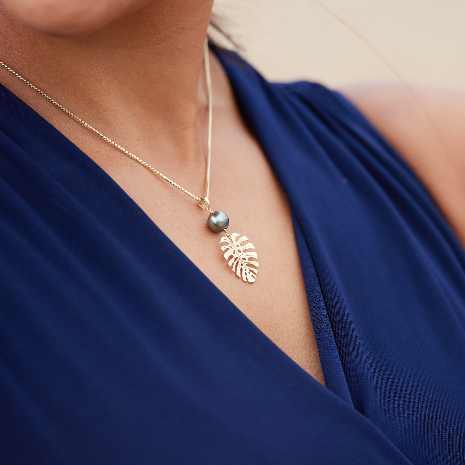 Close up of a 23mm Monstera Tahitian Black Pearl Pendant in Gold on a woman's chest