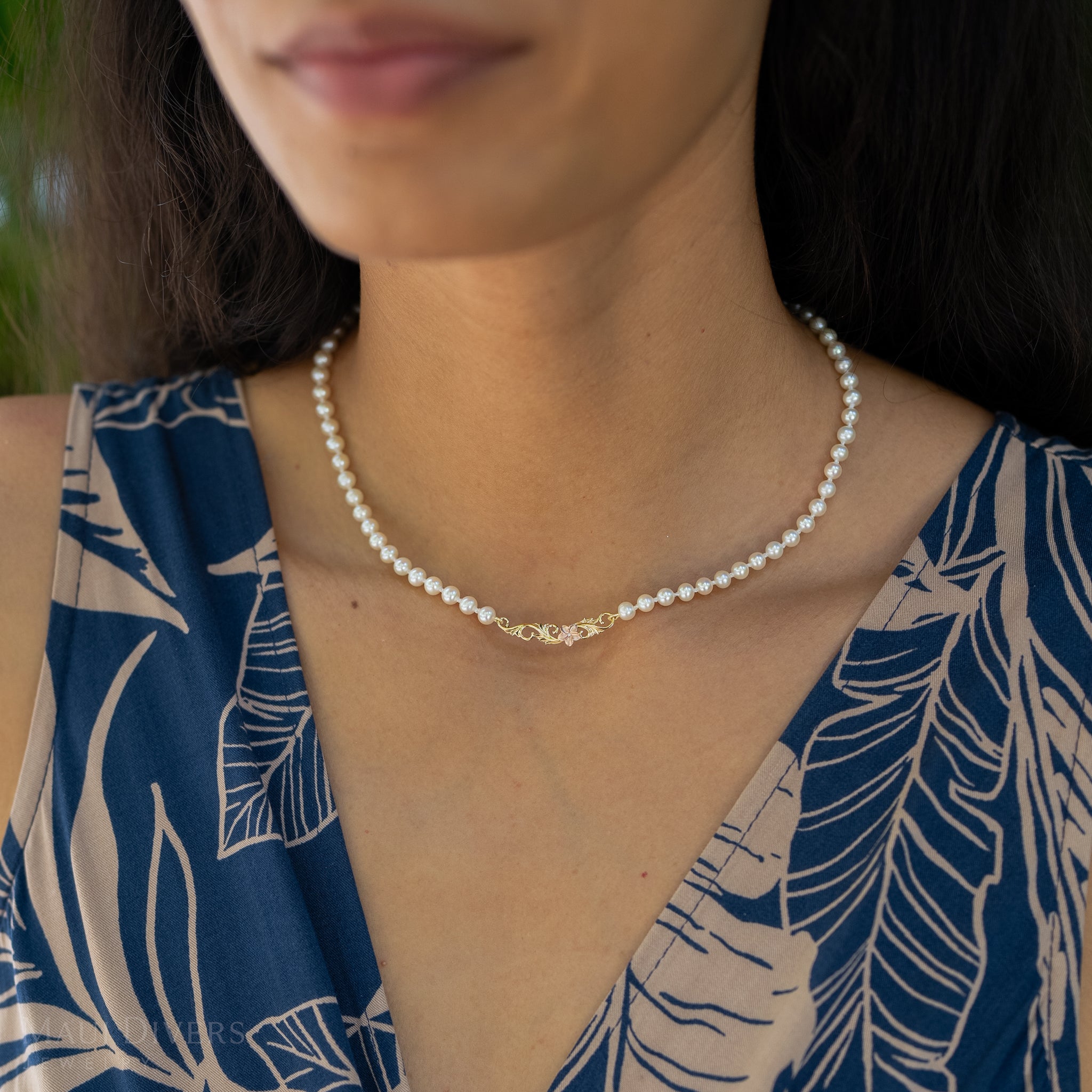 Close up of a woman wearing the Hawaiian Heirloom Plumeria Freshwater White Pearl Necklace
