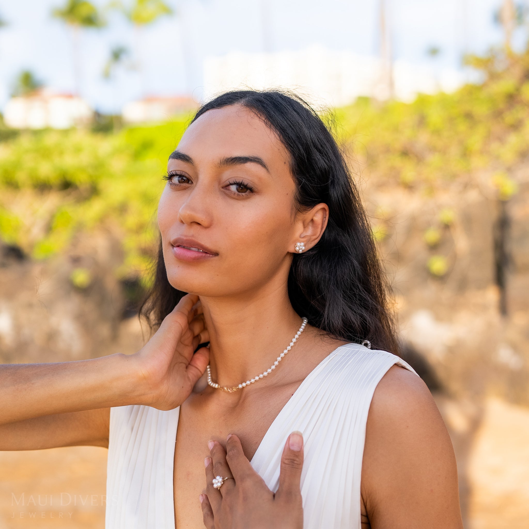 Woman in a white dress and pearl earrings wearing a Hawaiian Heirloom Plumeria Freshwater White Pearl Necklace