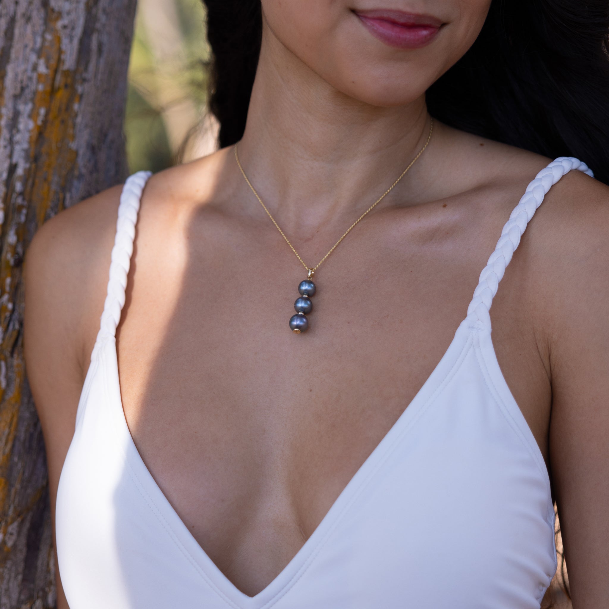 Three Stacked 10-11mm Tahitian Black Pearl Pendant in Gold on a woman's chest