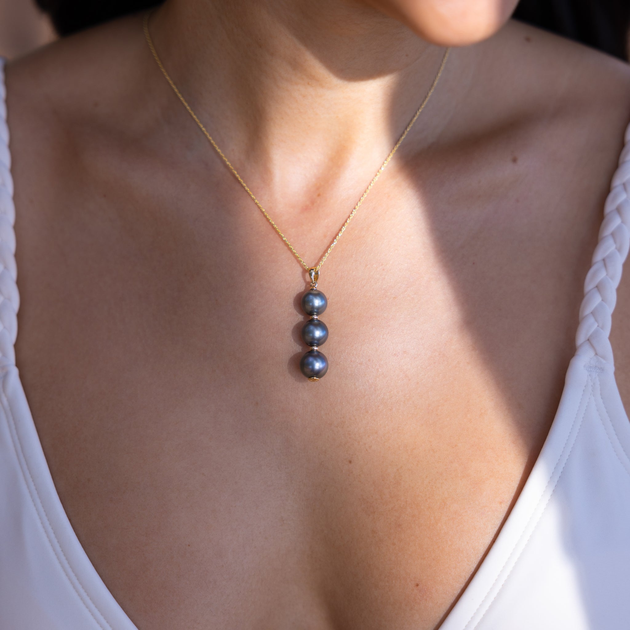 Close up of a Three Stacked 10-11mm Tahitian Black Pearl Pendant in Gold on a woman's chest