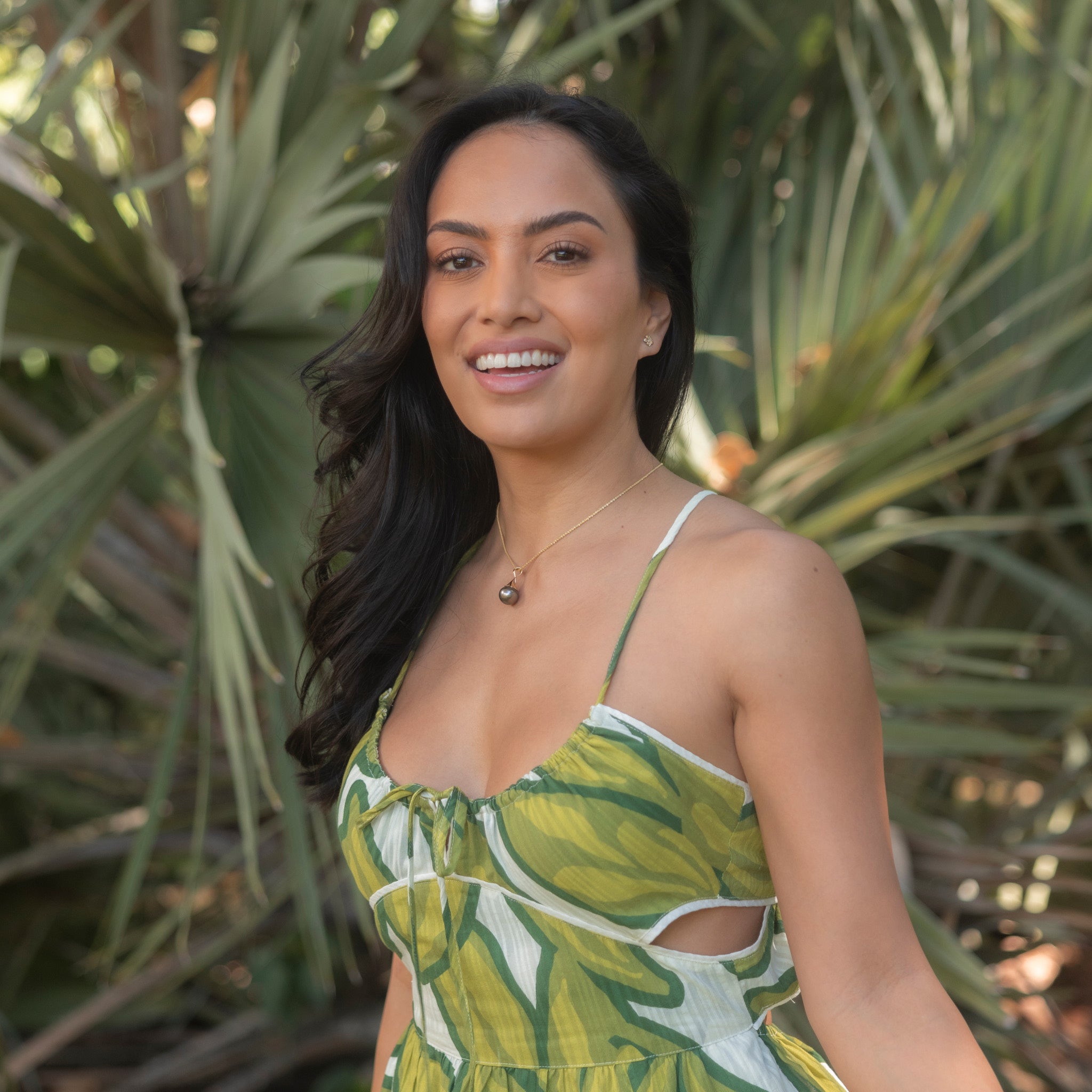 Woman in a garden wearing a Waterfall Circle 12-14mm Tahitian Black Pearl Pendant in Gold