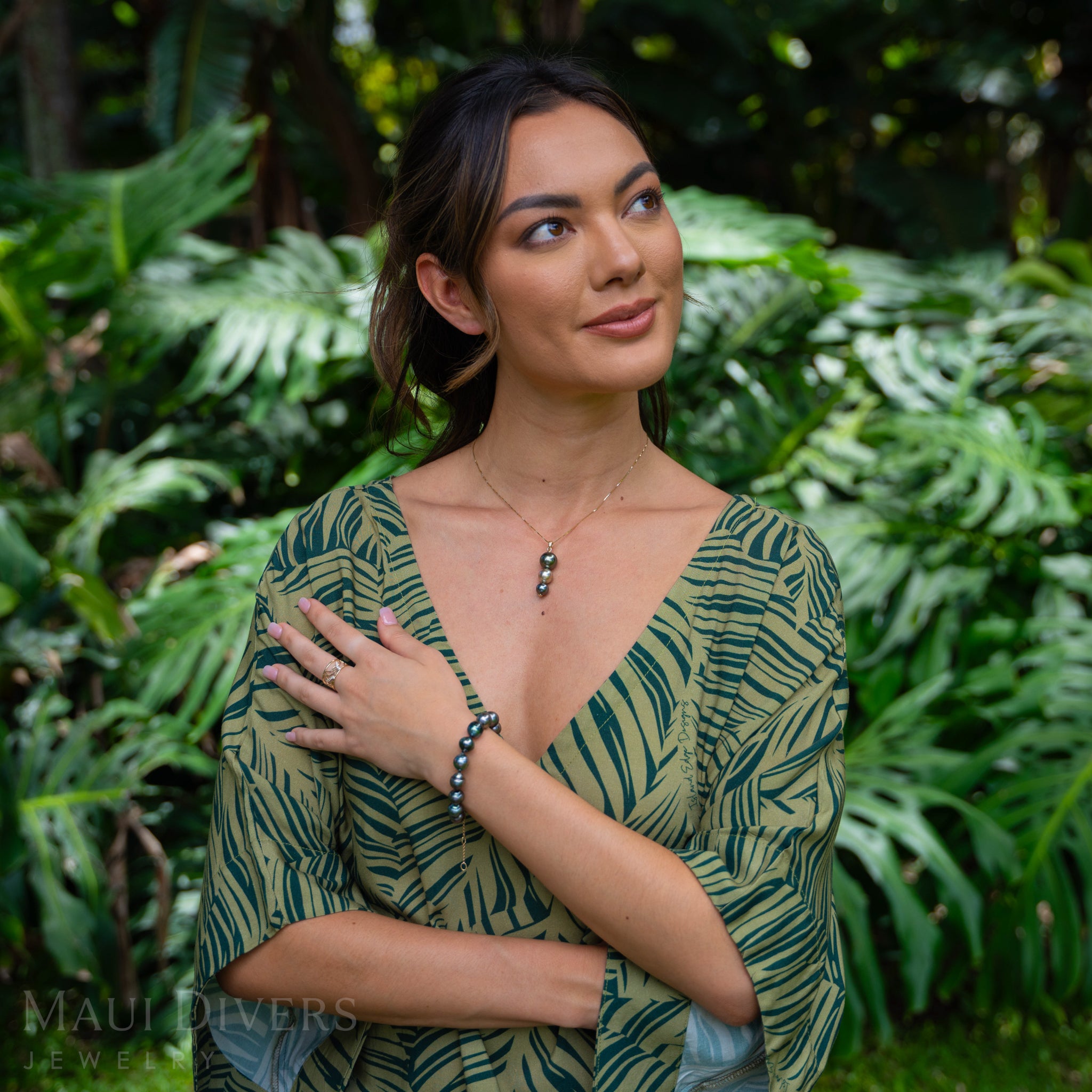 Woman in a garden wearing a Three-tiered Tahitian Black Pearl Pendant in Gold and matching pearl bracelet