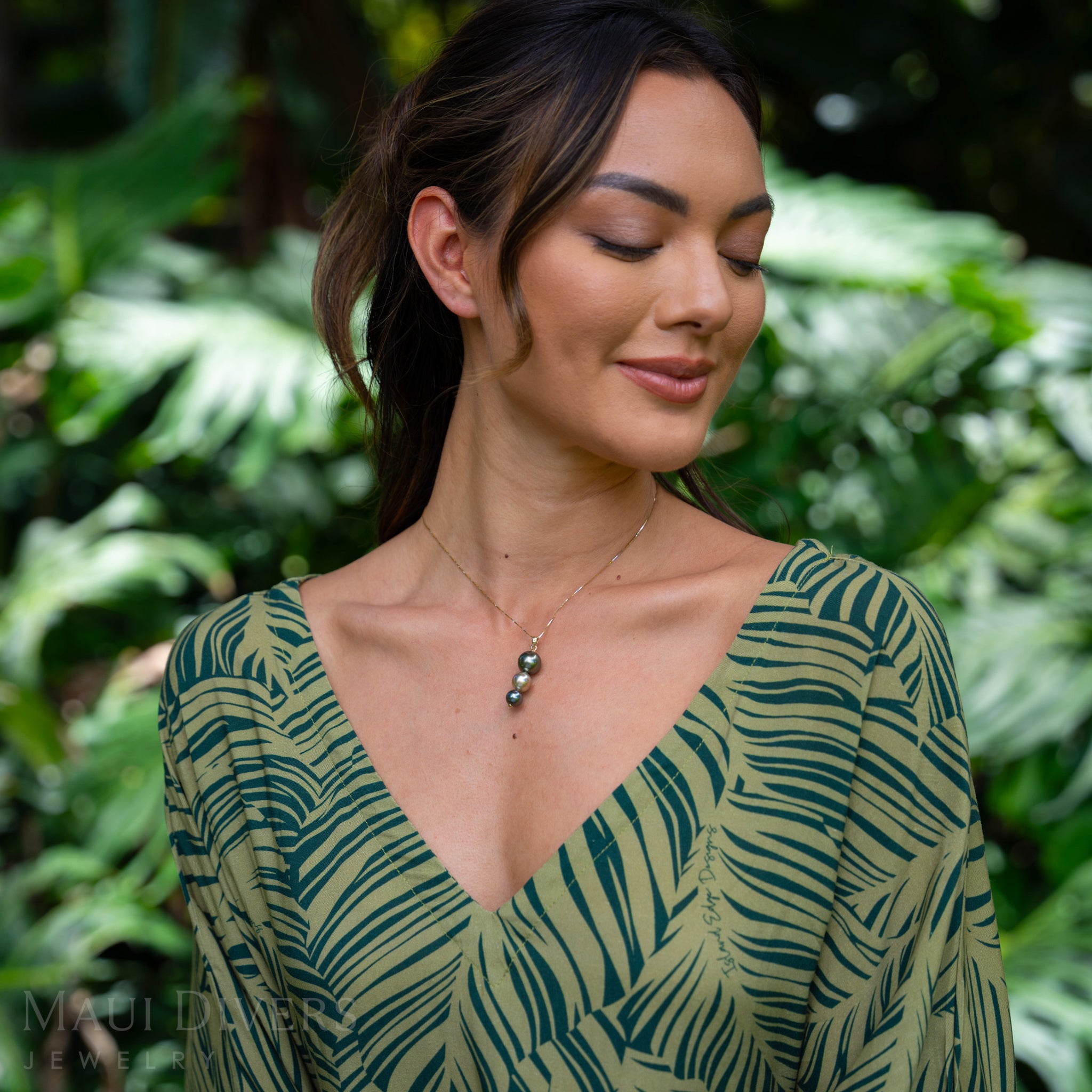Woman in a garden wearing a Three-tiered 8-13mm Tahitian Black Pearl Pendant in Gold