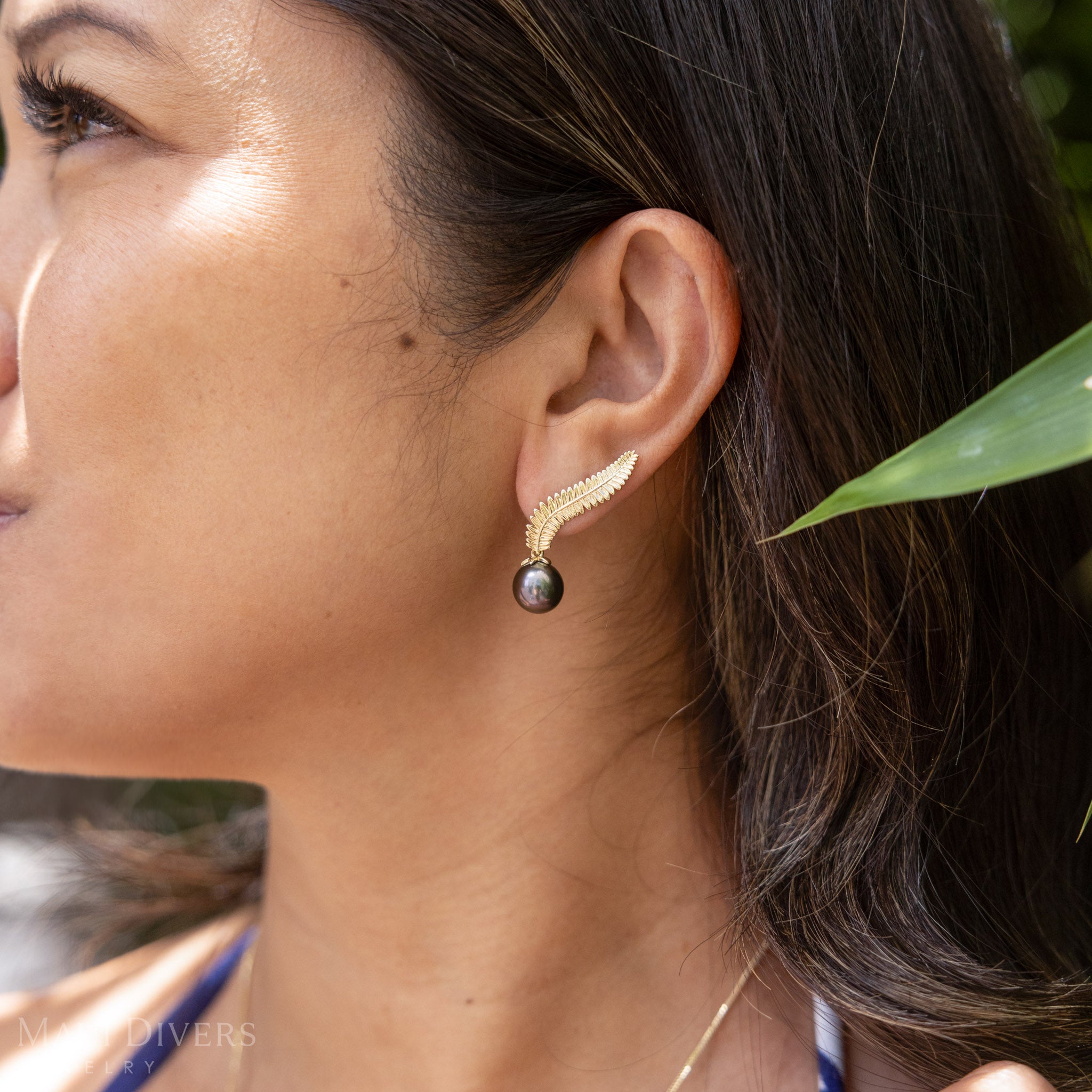 Close up of an ear wearing the kupukupu fern Tahitian black pearl climber earring