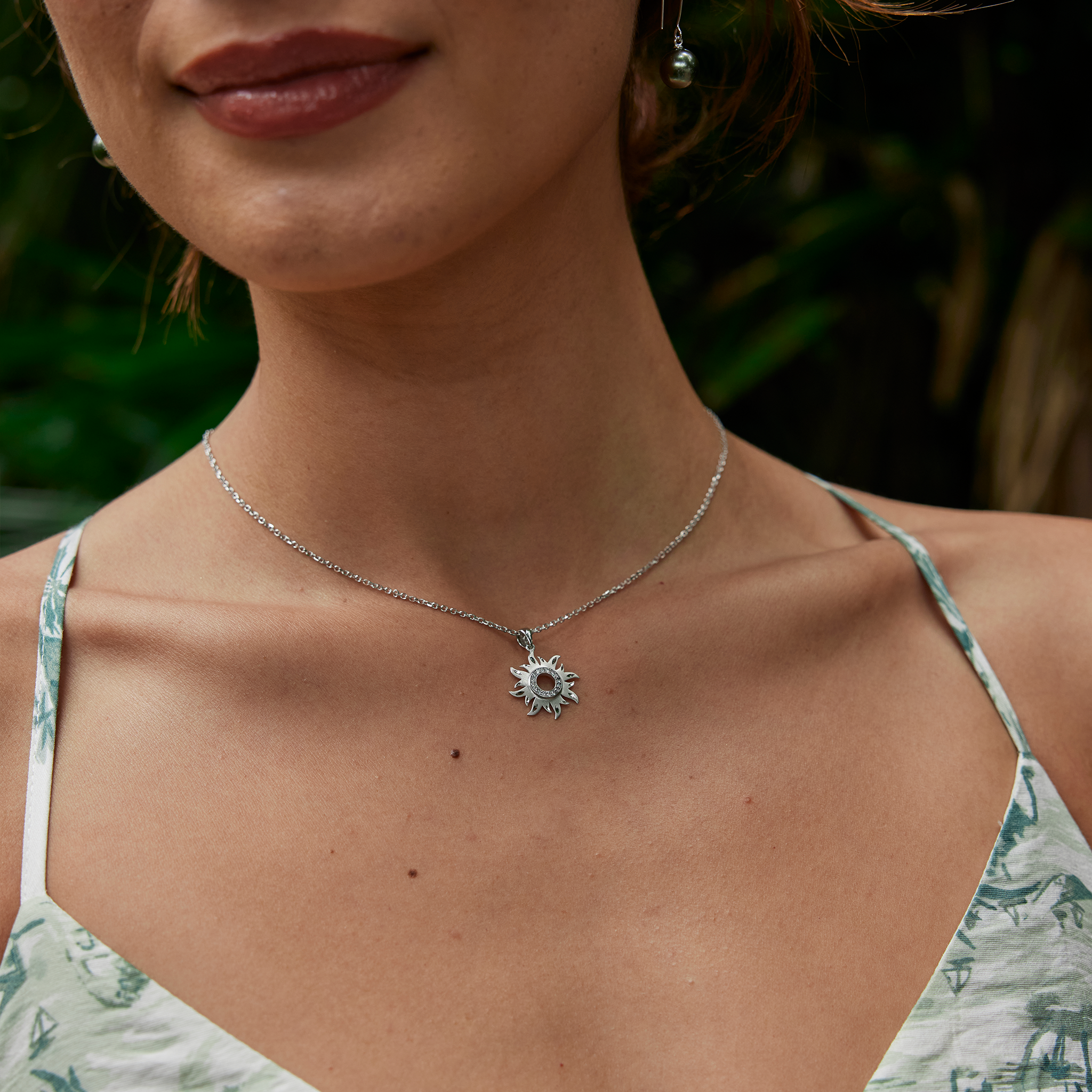 Woman's neckline featuring white gold sun pendant with diamonds