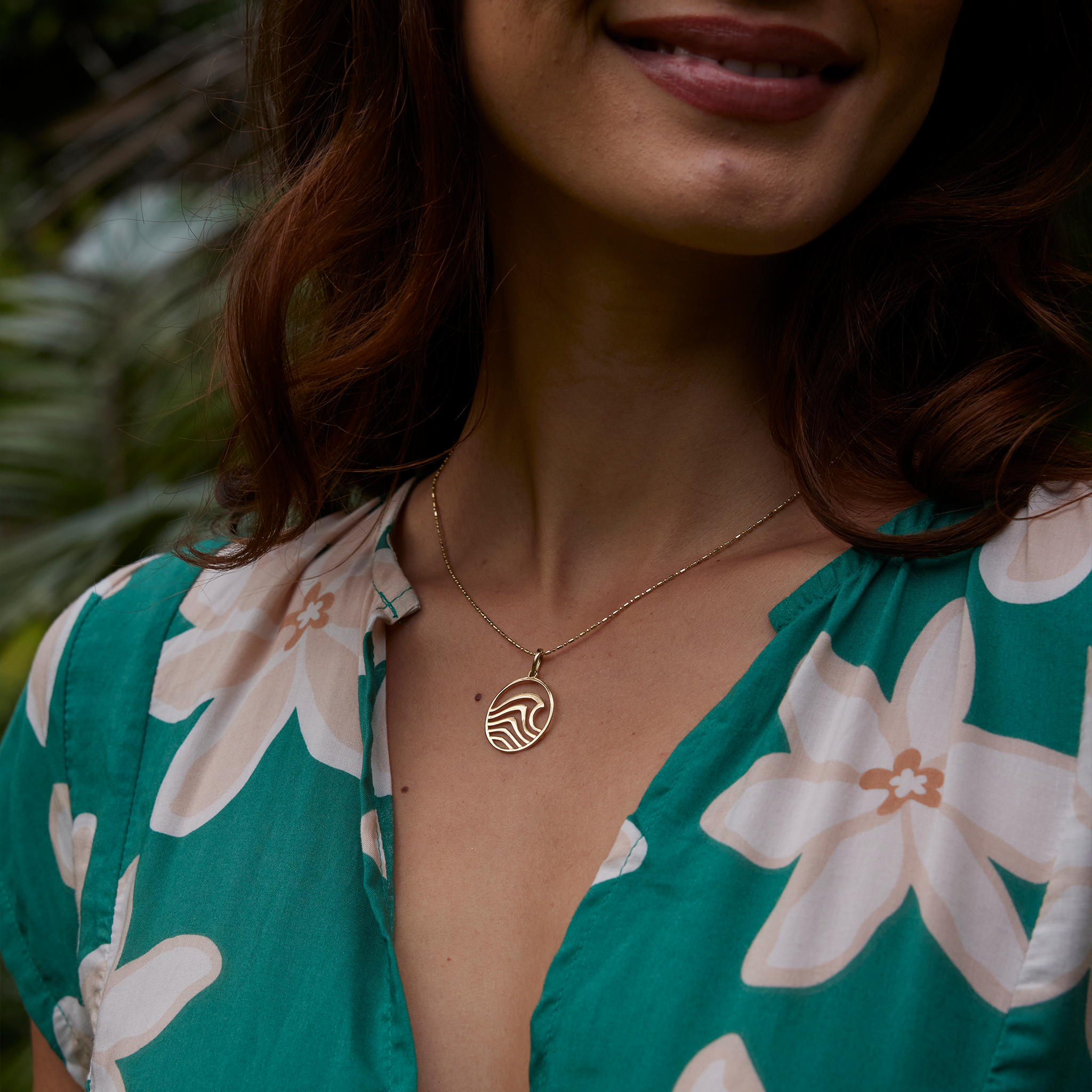 Close up of a woman wearing an abstract wave necklace in gold