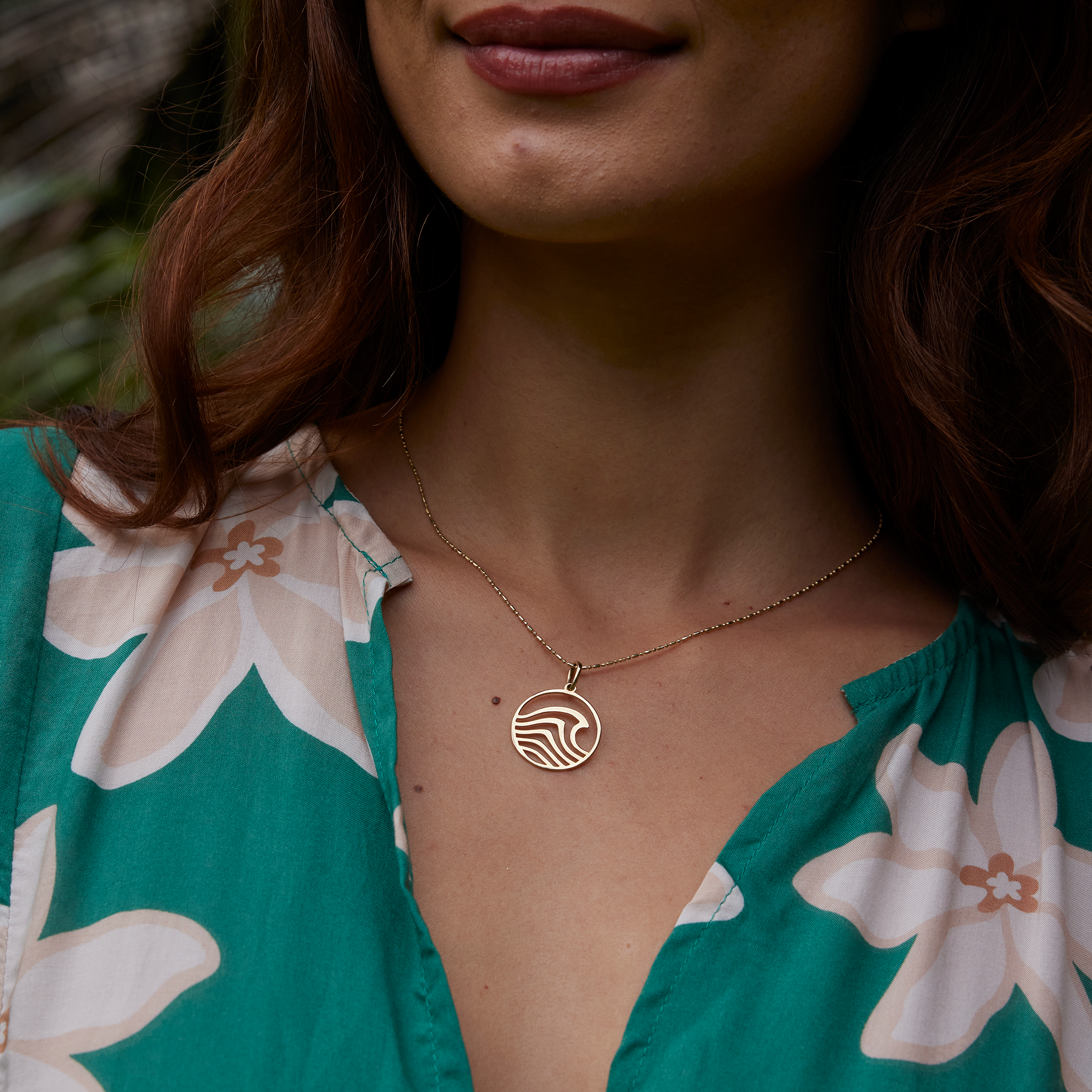 Close up of a woman wearing an abstract wave necklace in gold
