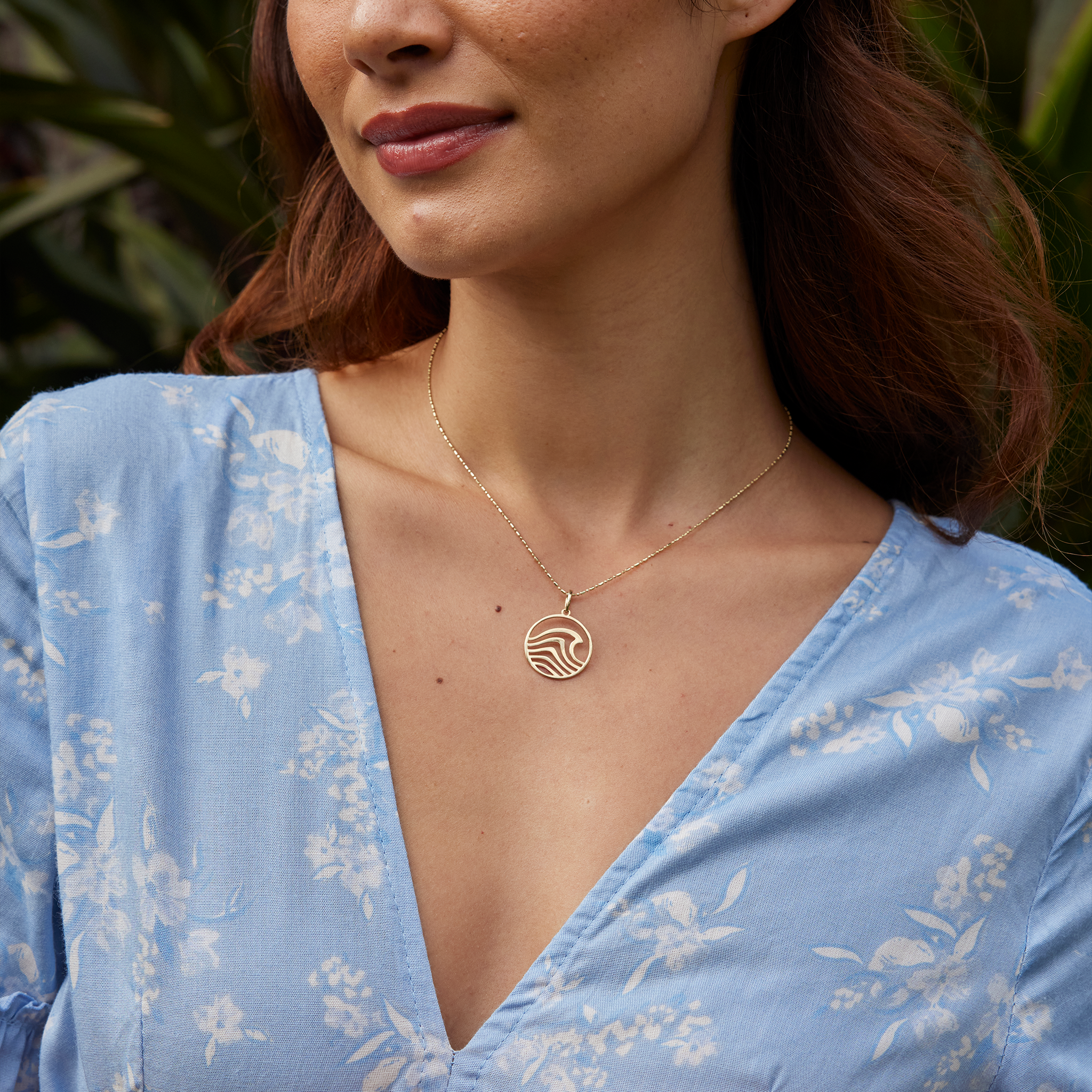 Close up of a woman wearing an abstract wave necklace in gold