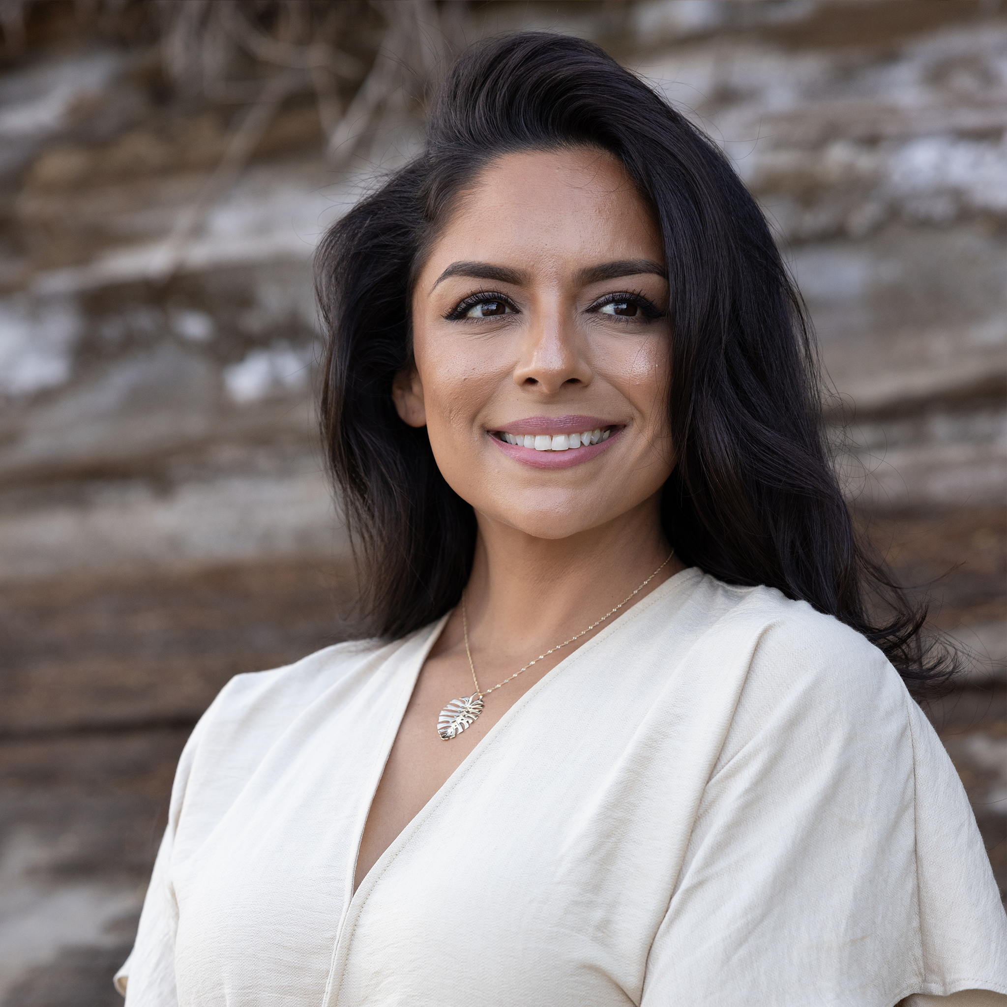 Woman wearing gold monstera leaf pendant with high polish finish
