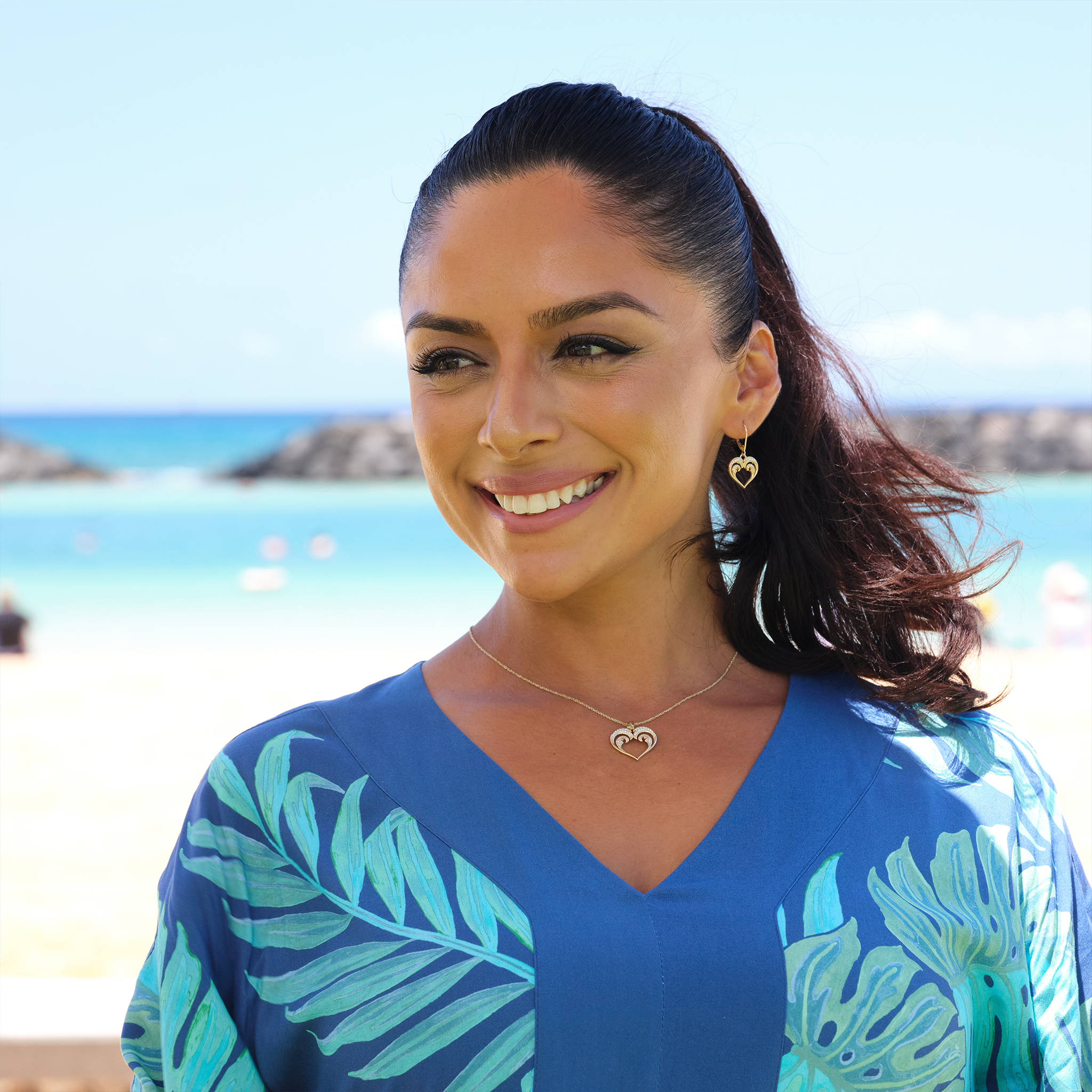 A woman wearing a Nalu Heart Pendant with Diamonds in Gold - 20mm-Maui Divers Jewelry