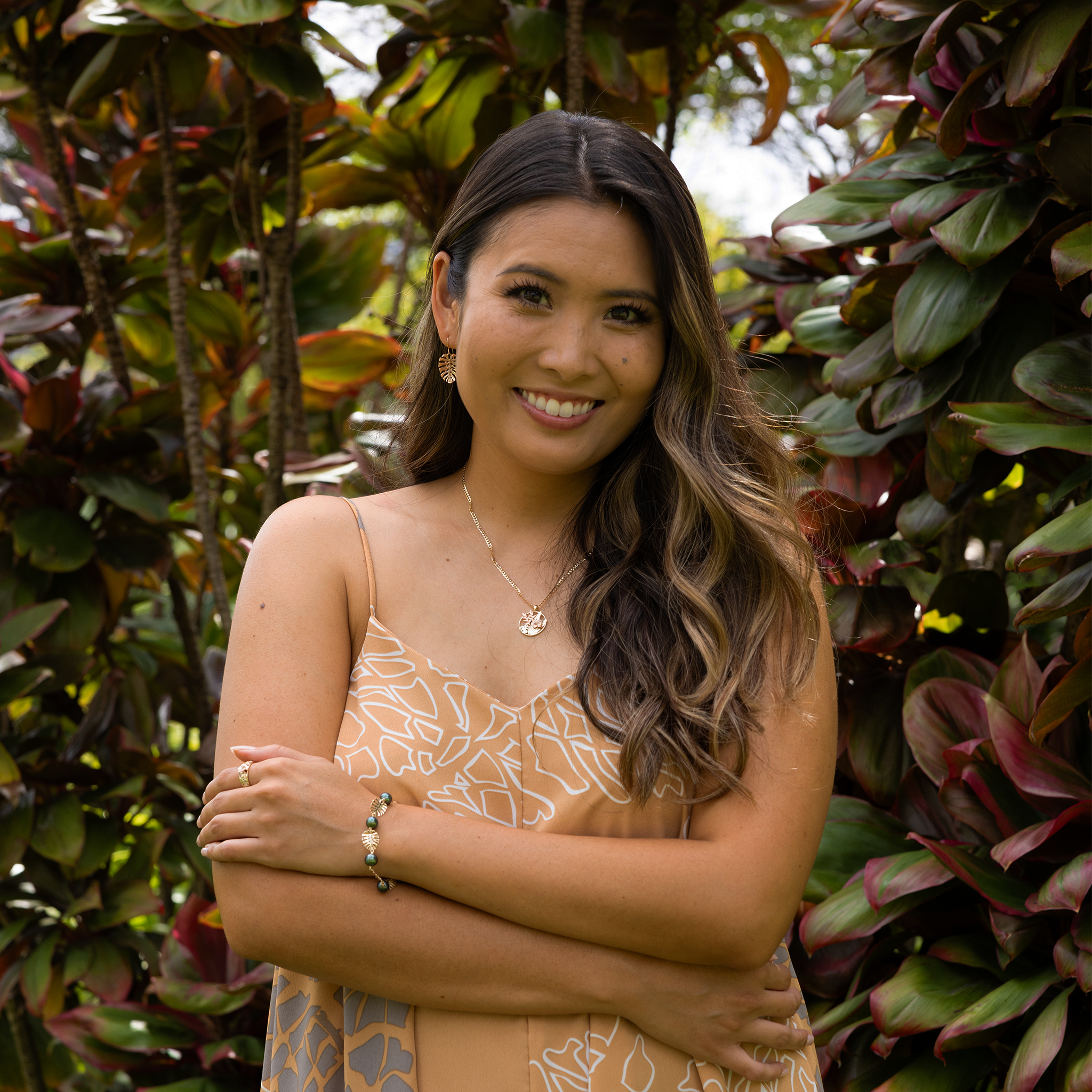 A woman wearing a Hawaiian Gardens Hibiscus Pendant in Tri Color Gold with Diamonds