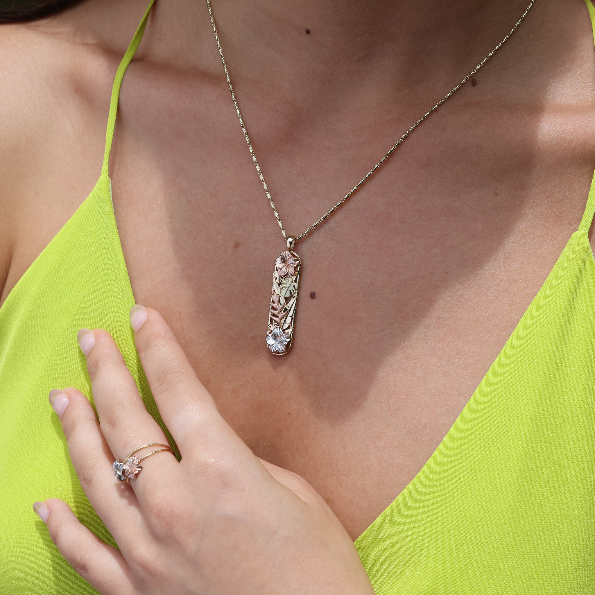 A woman wearing a Hawaiian Gardens Hibiscus Pendant in Multi Color Gold with Diamonds