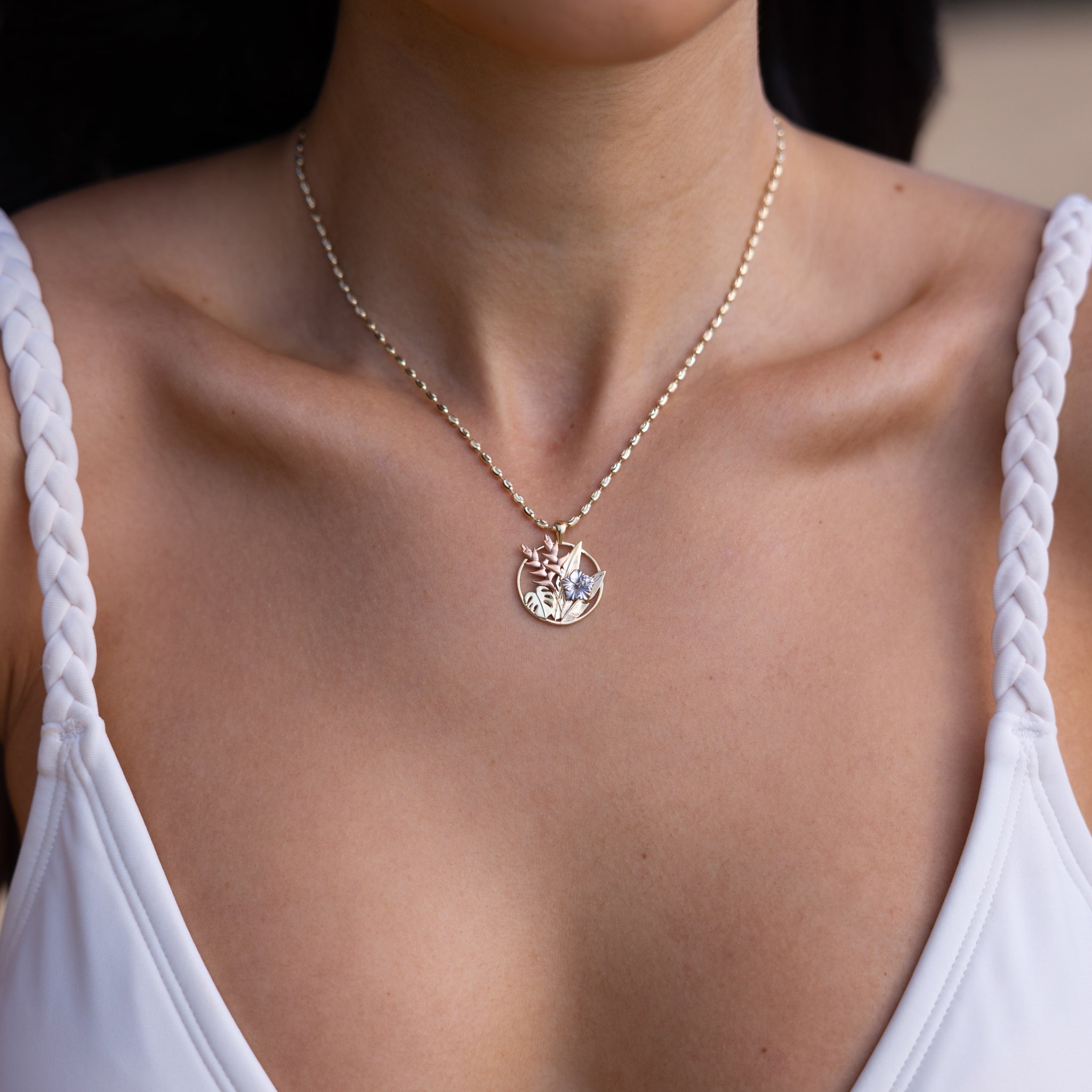 Close up of woman wearing Hawaiian Gardens Pendant in four tone gold with diamonds