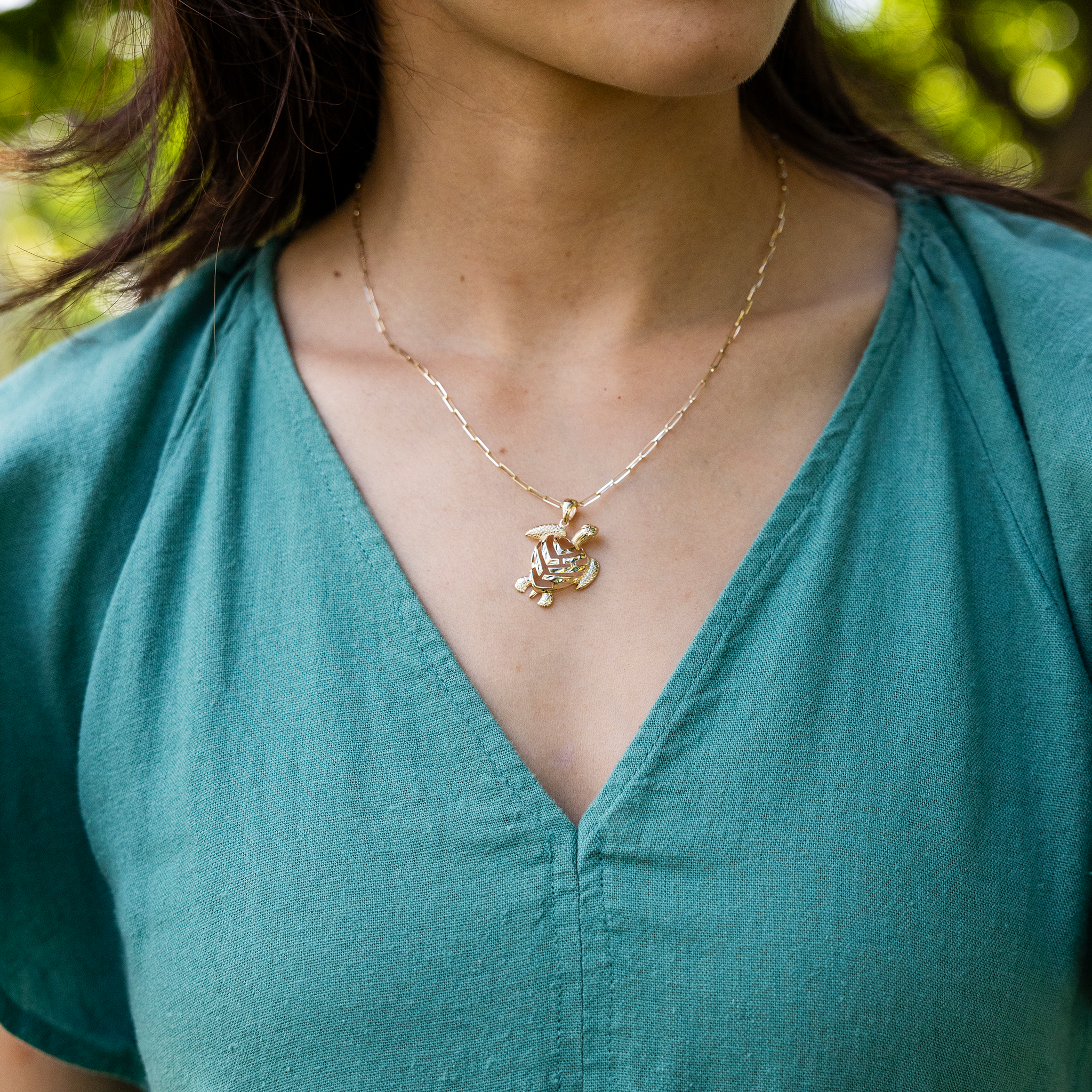 Woman wearing a Honu Aloha Heart Pendant in Gold on paperclip chain with green dress