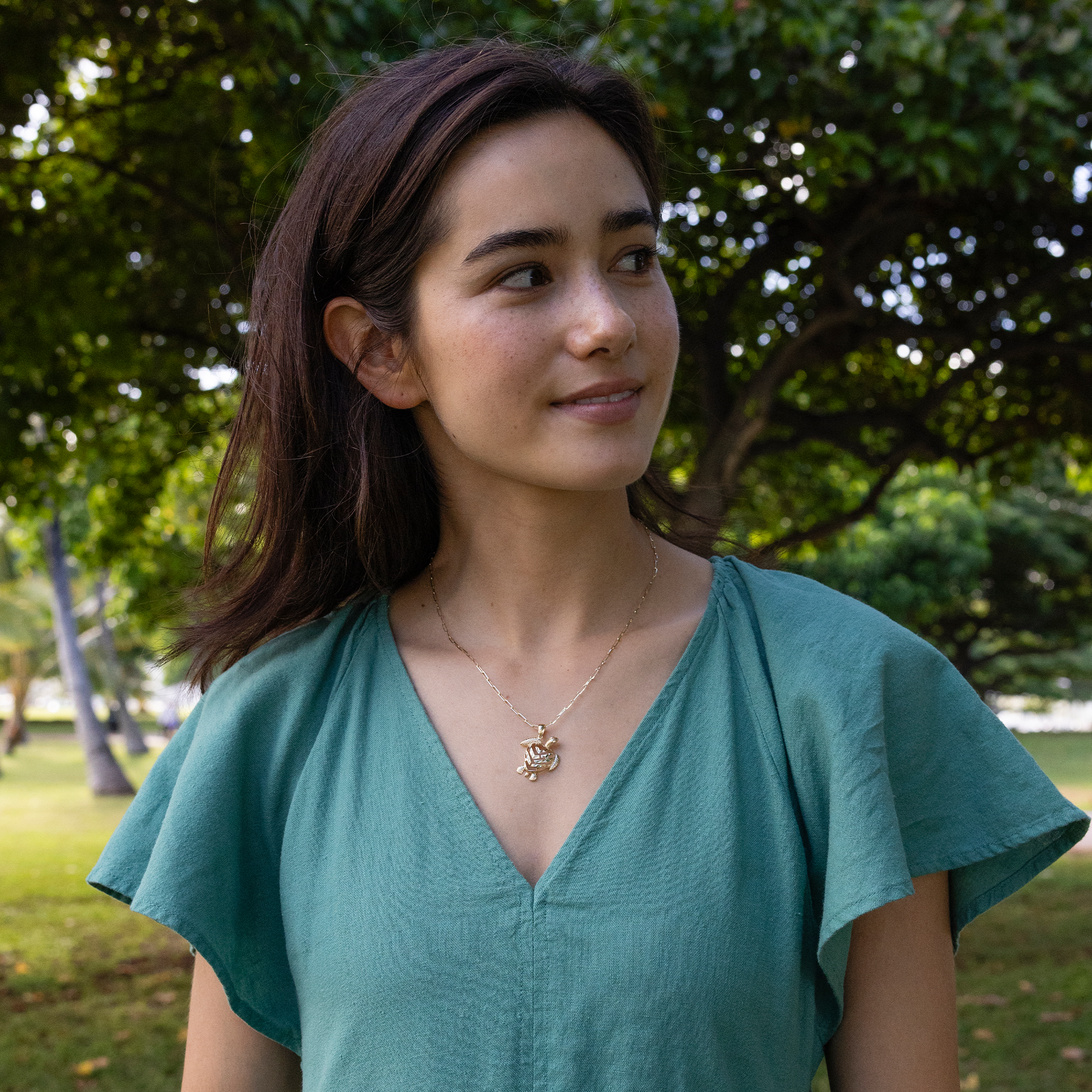 Woman wearing a Honu Aloha Heart Pendant in Gold on paperclip chain with green dress