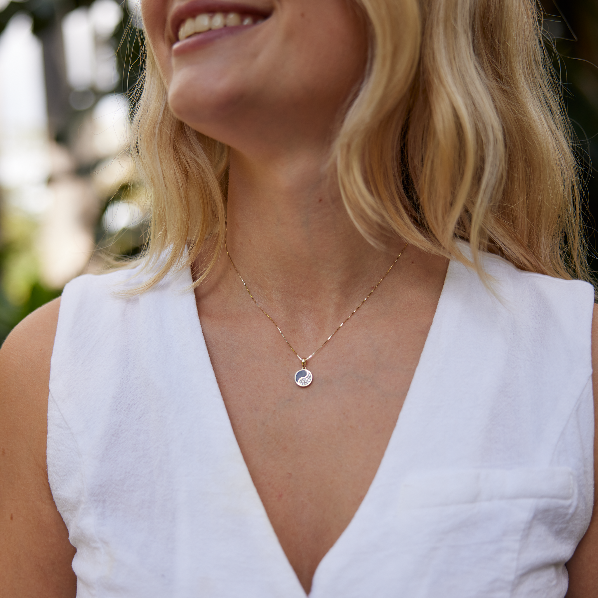 woman in white wearing Yin Yang Black Coral Pendant in Gold with Diamonds - 10mm