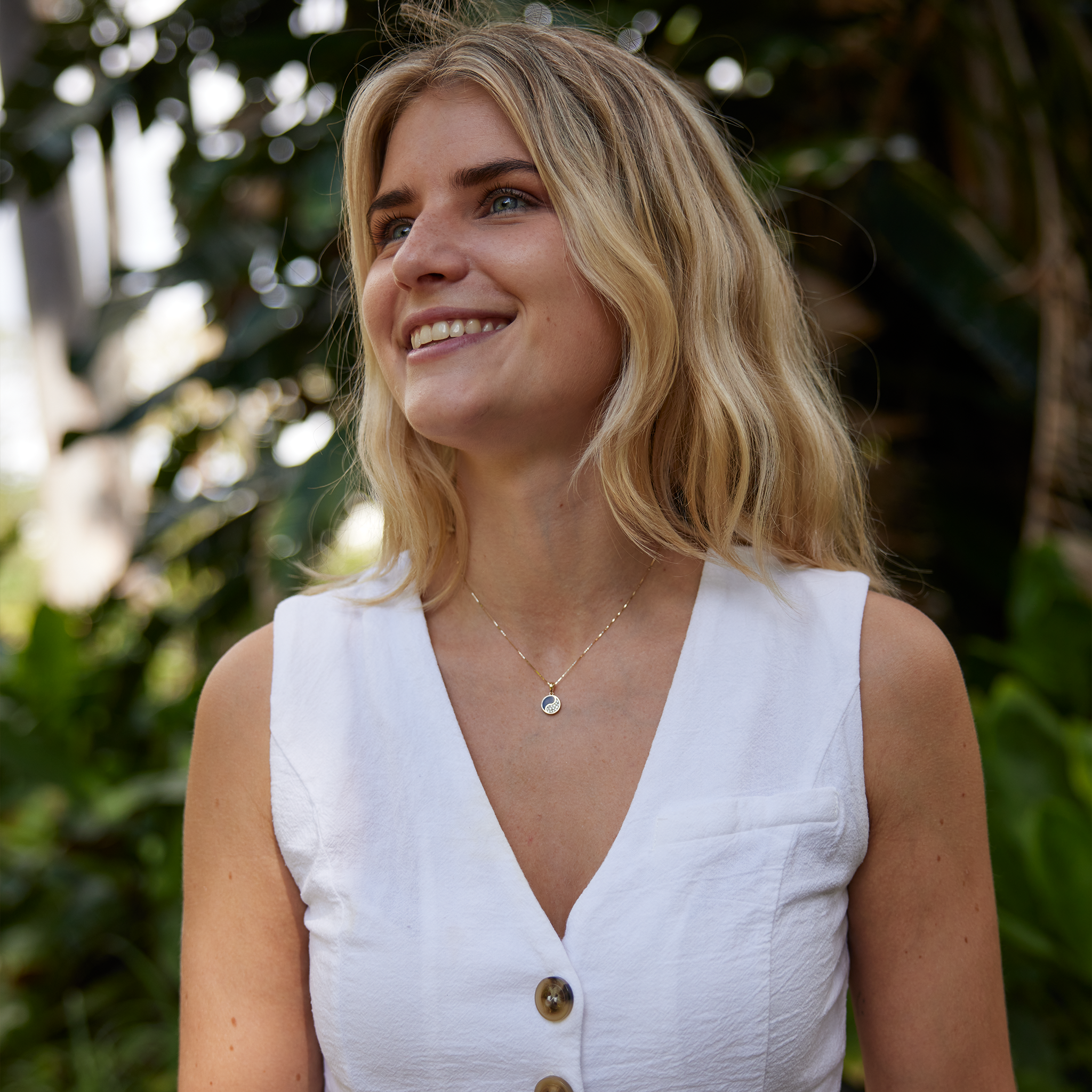 Woman wearing a white v-neck shirt wearing Yin Yang Black Coral Pendant in Gold with Diamonds - 10mm