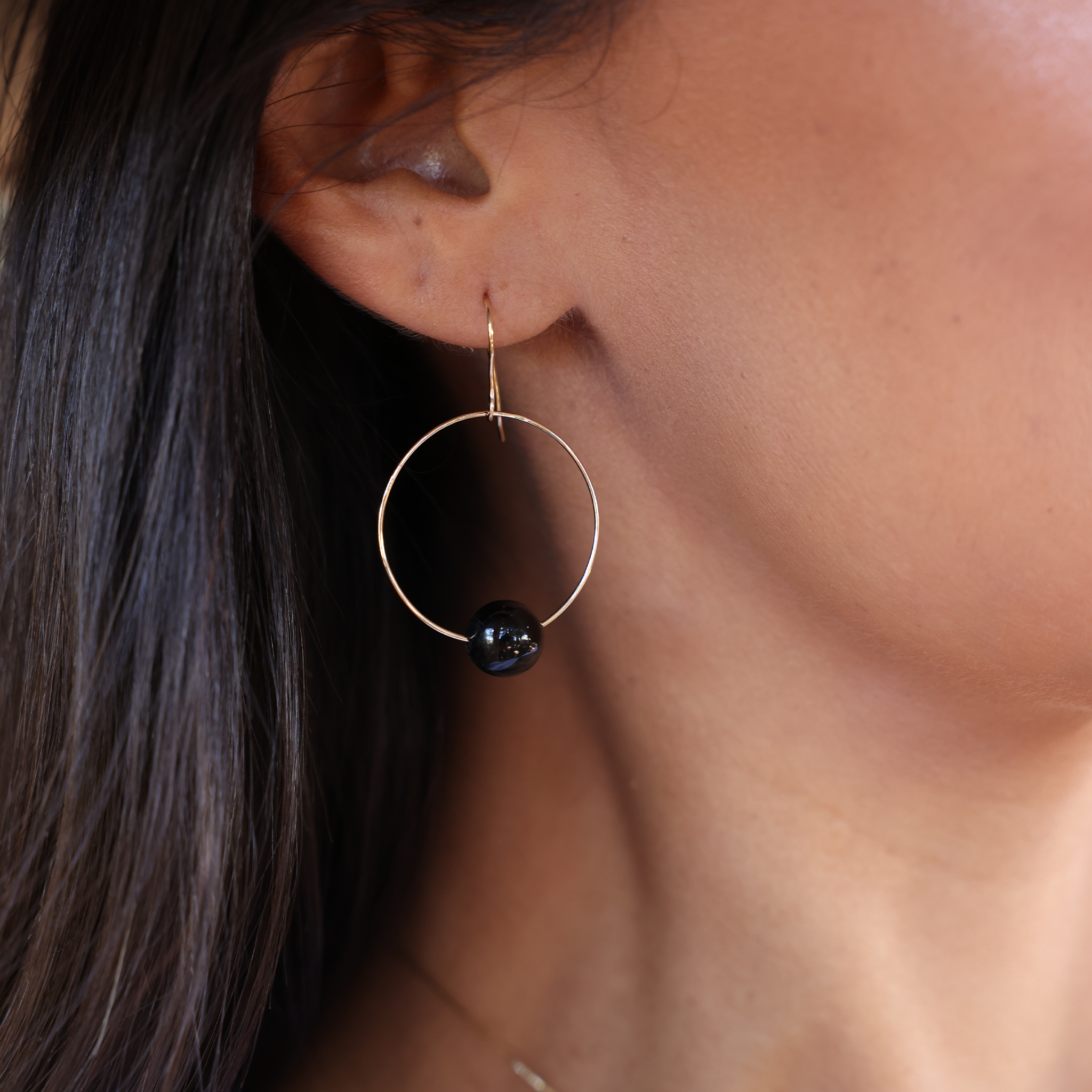 Woman's ear wearing Hawaiian Black Coral Hoop Earrings in Gold