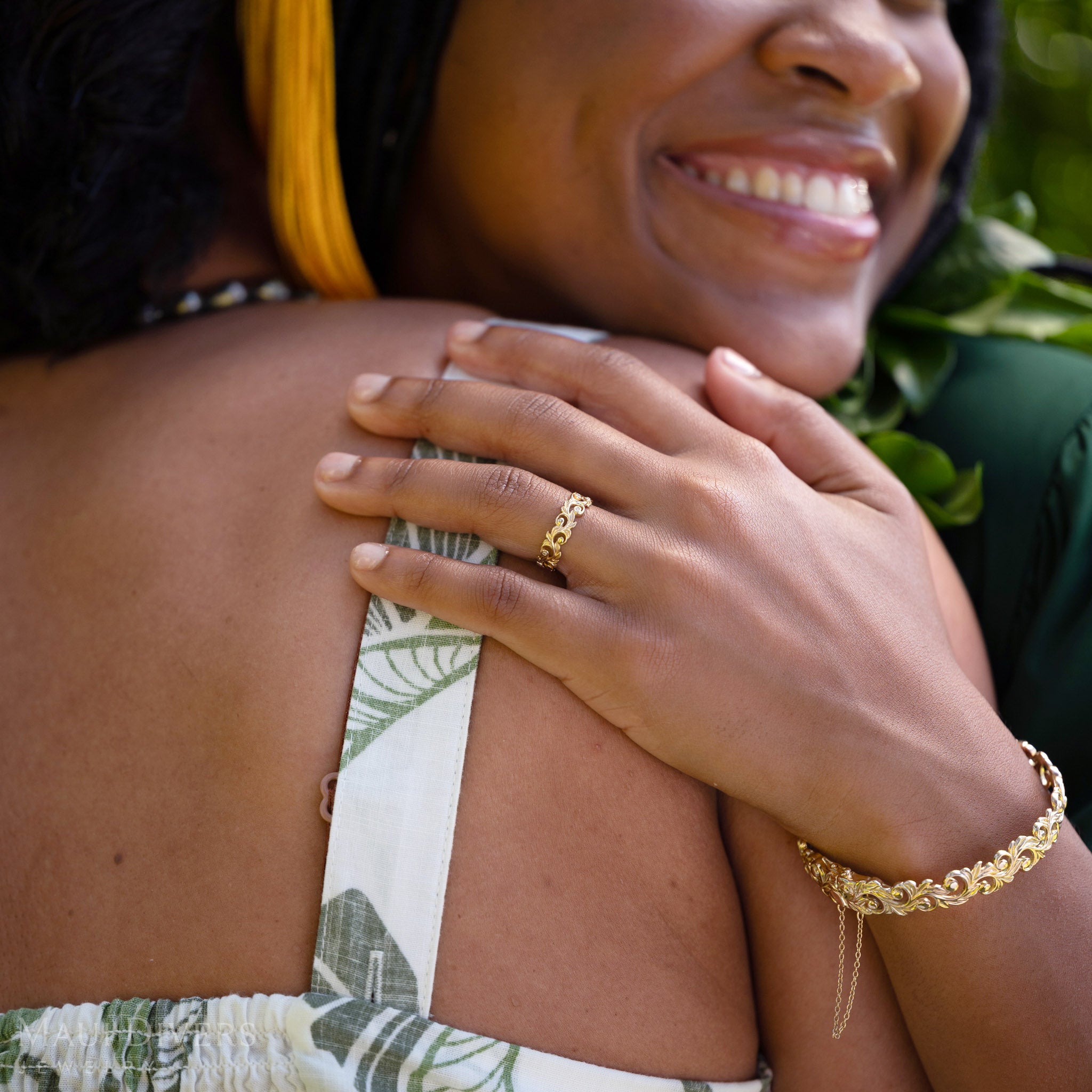 Smiling woman wearing a a Living Heirloom Ring in 14k yellow gold with diamond accents on her ring finger, hugging another person