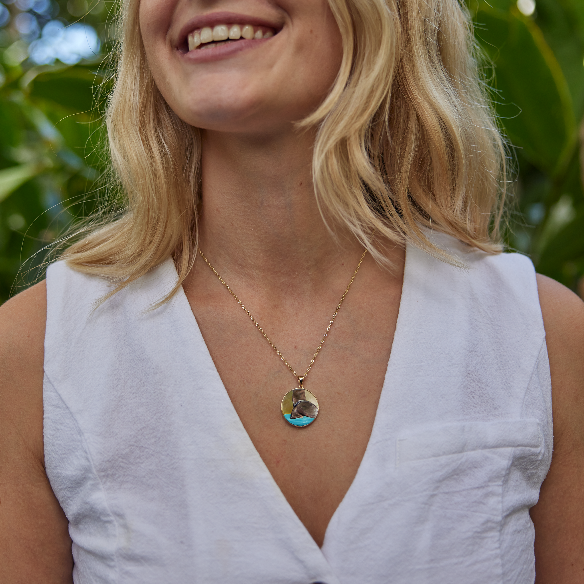 Woman in garden wearing Hawaiian Moments Whale Tail Mother of Pearl & Turquoise Pendant in Gold - 22mm