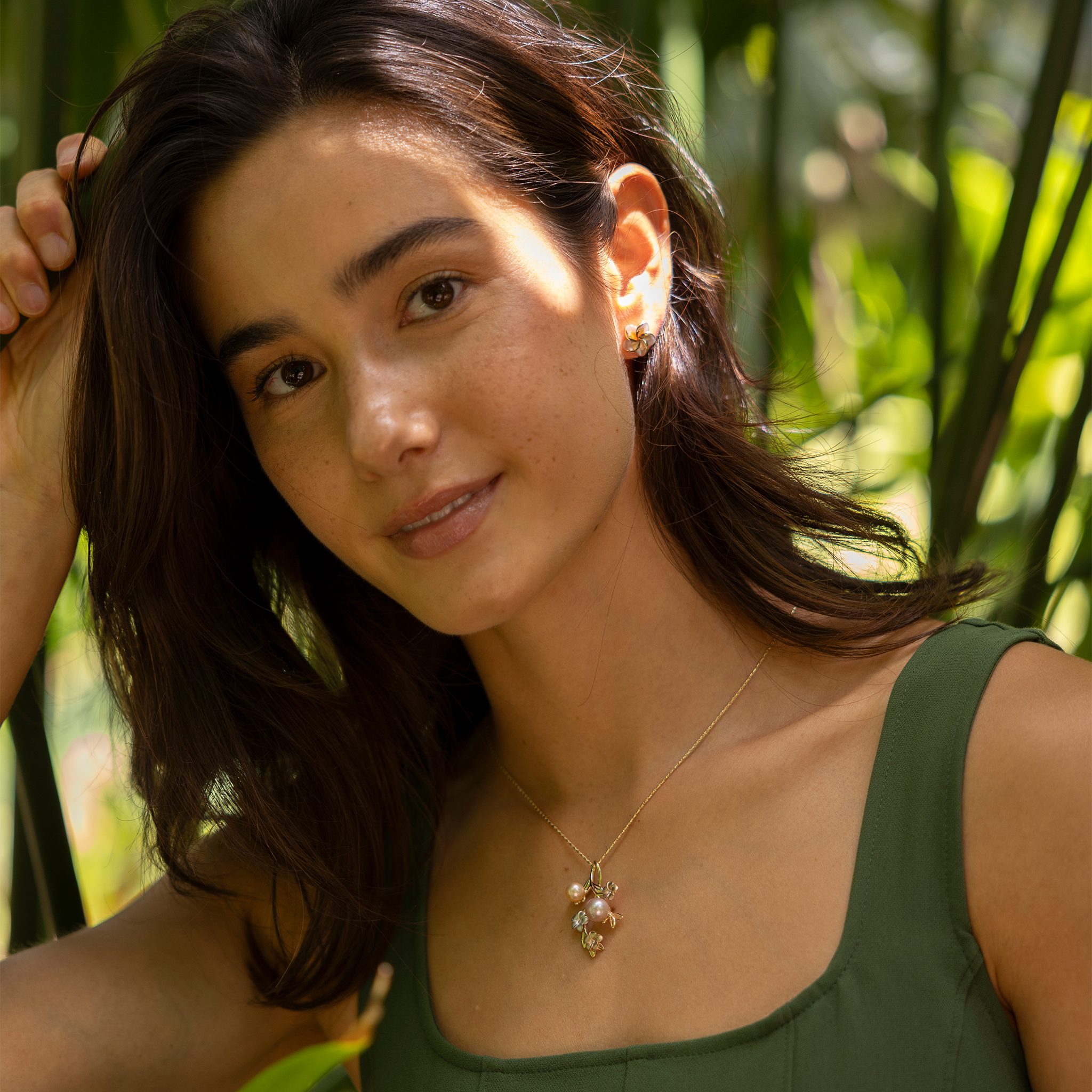 Woman in tropical garden wearing Plumeria Mother of Pearl Earrings in 14k Yellow Gold