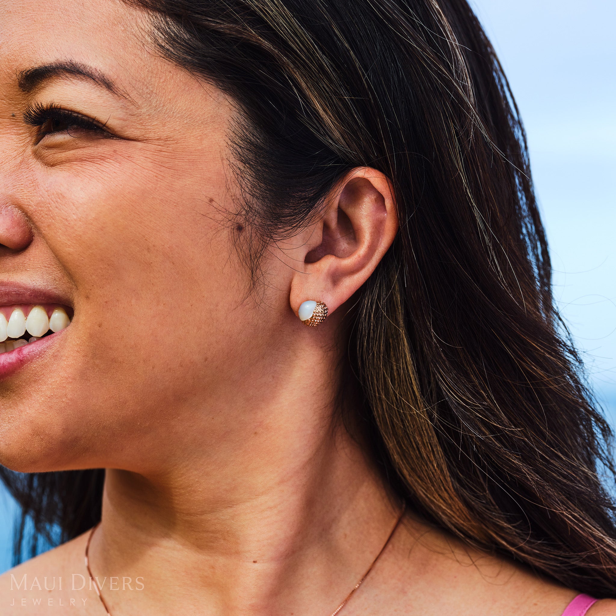 Close-up of a smiling woman wearing a Cute Fruits Lychee Mother of Pearl Earring in 14k Rose Gold on her ear