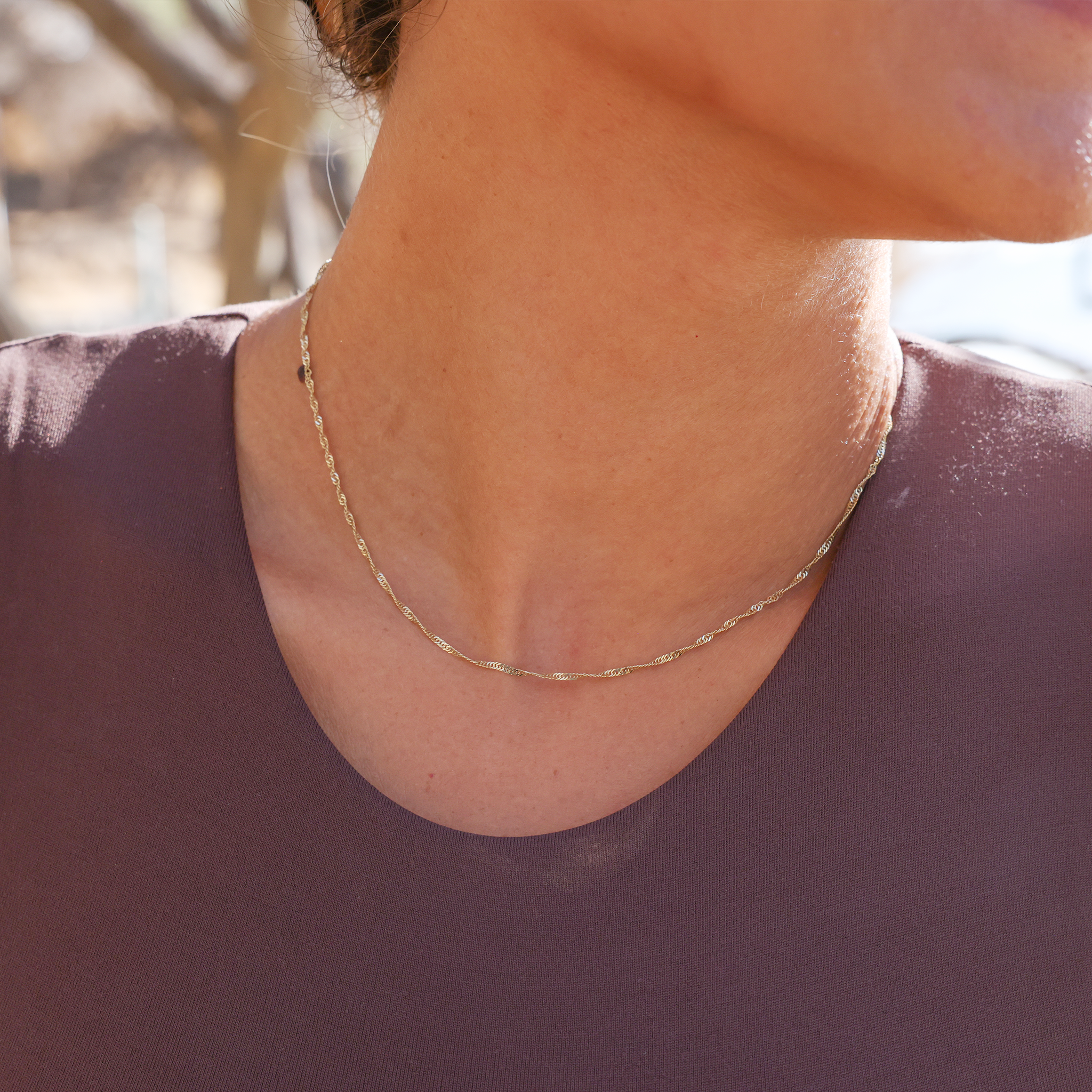 Close up of 1.5mm Singapore Chain in Gold on woman's neckline