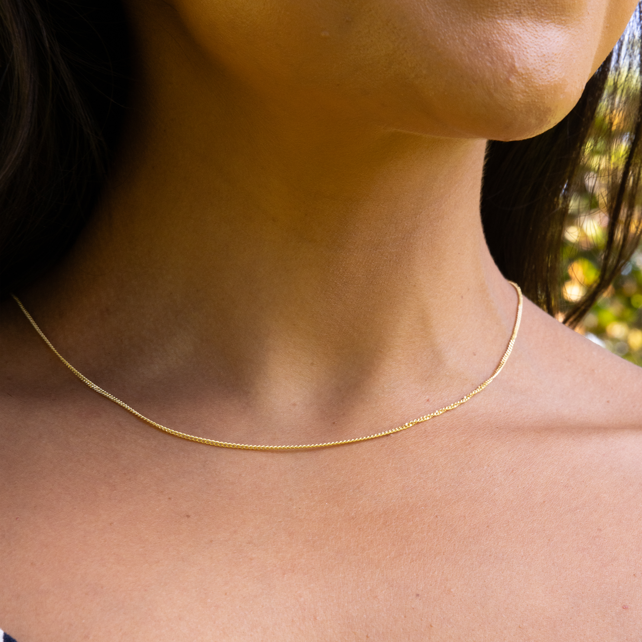 Close up of 1.5mm Gourmette Chain in 14k Yellow Gold on a neckline