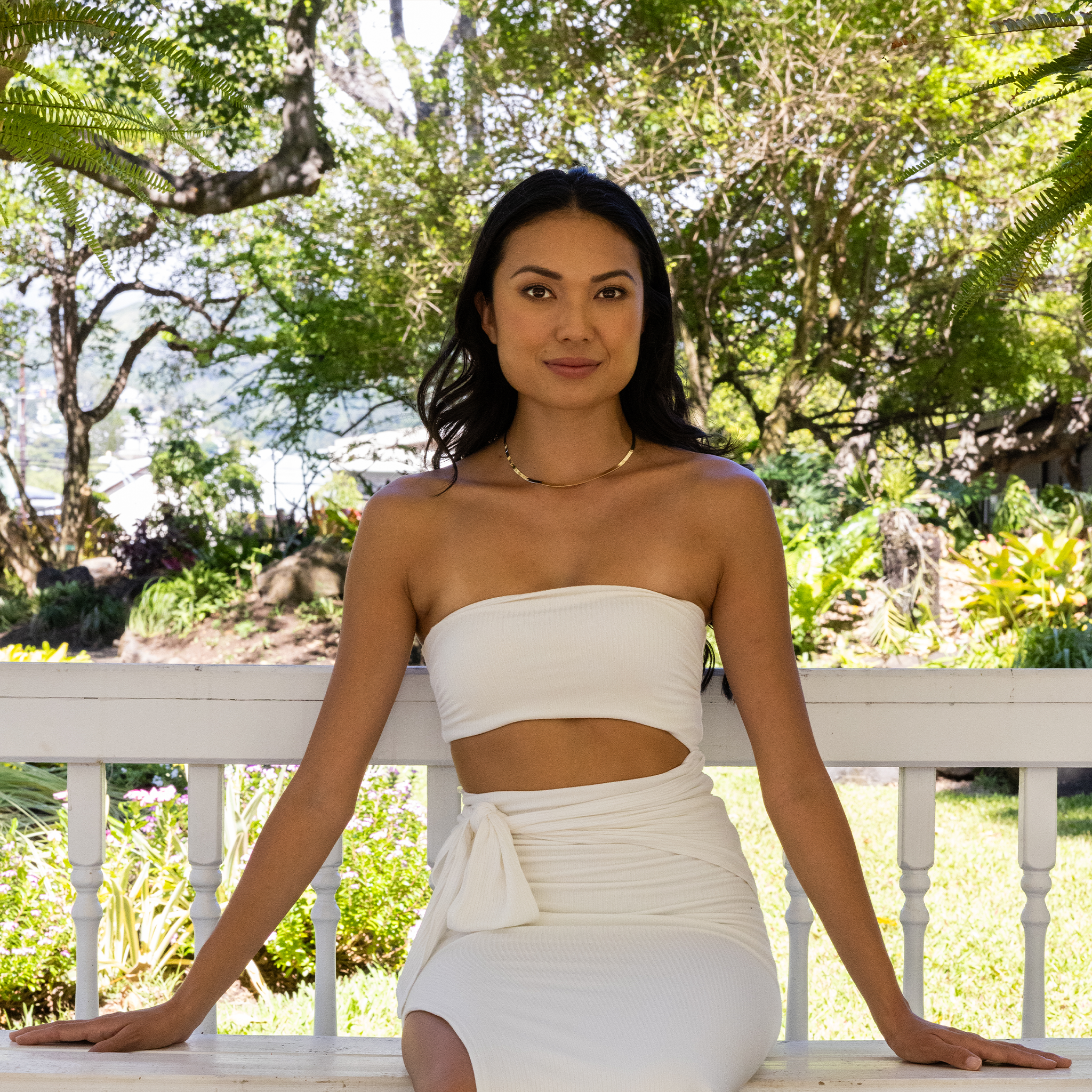 Woman in a garden gazebo wearing 3.8mm Herringbone Chain in 14k Yellow Gold and white dress