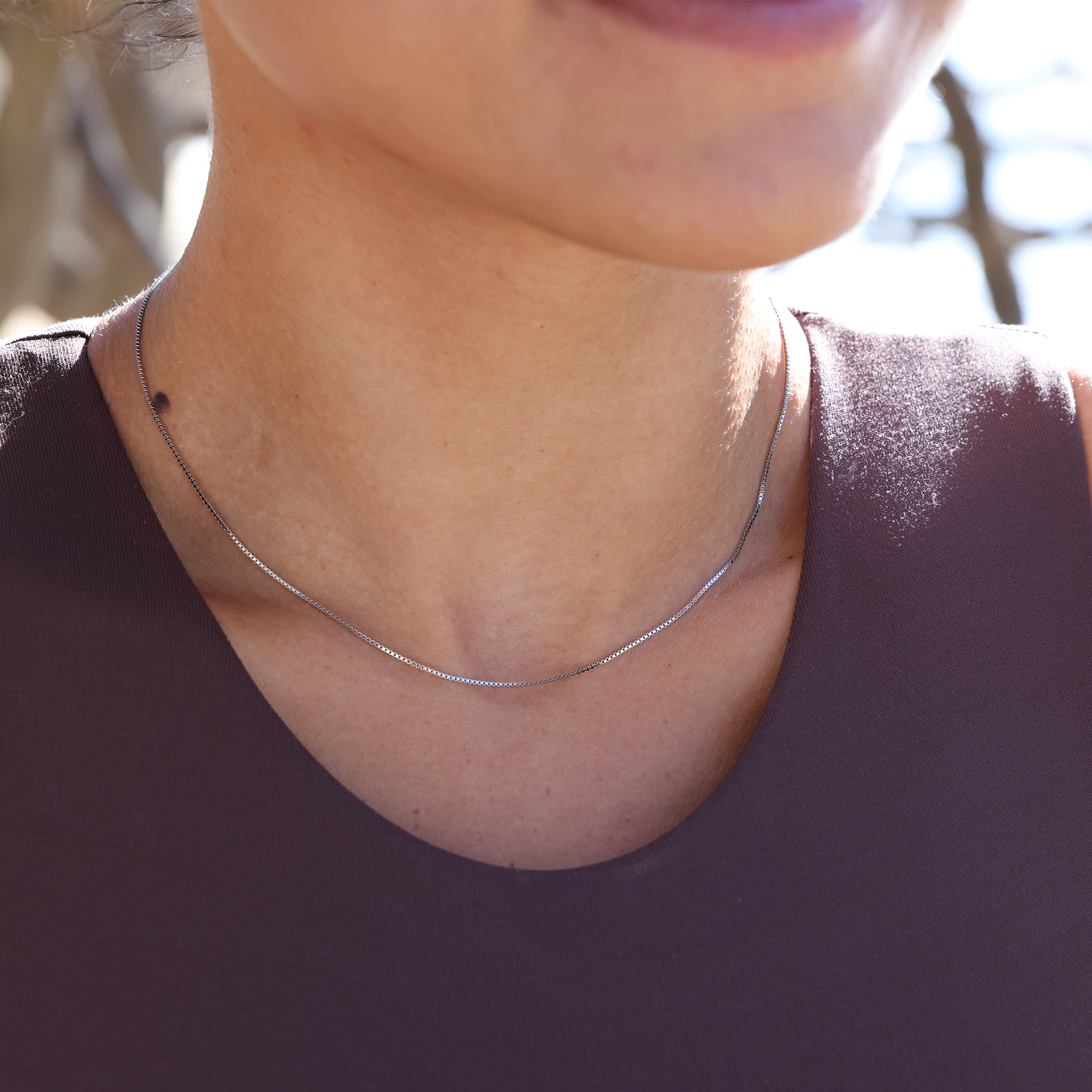 Close-up of a person wearing a 1.0mm box chain outdoors