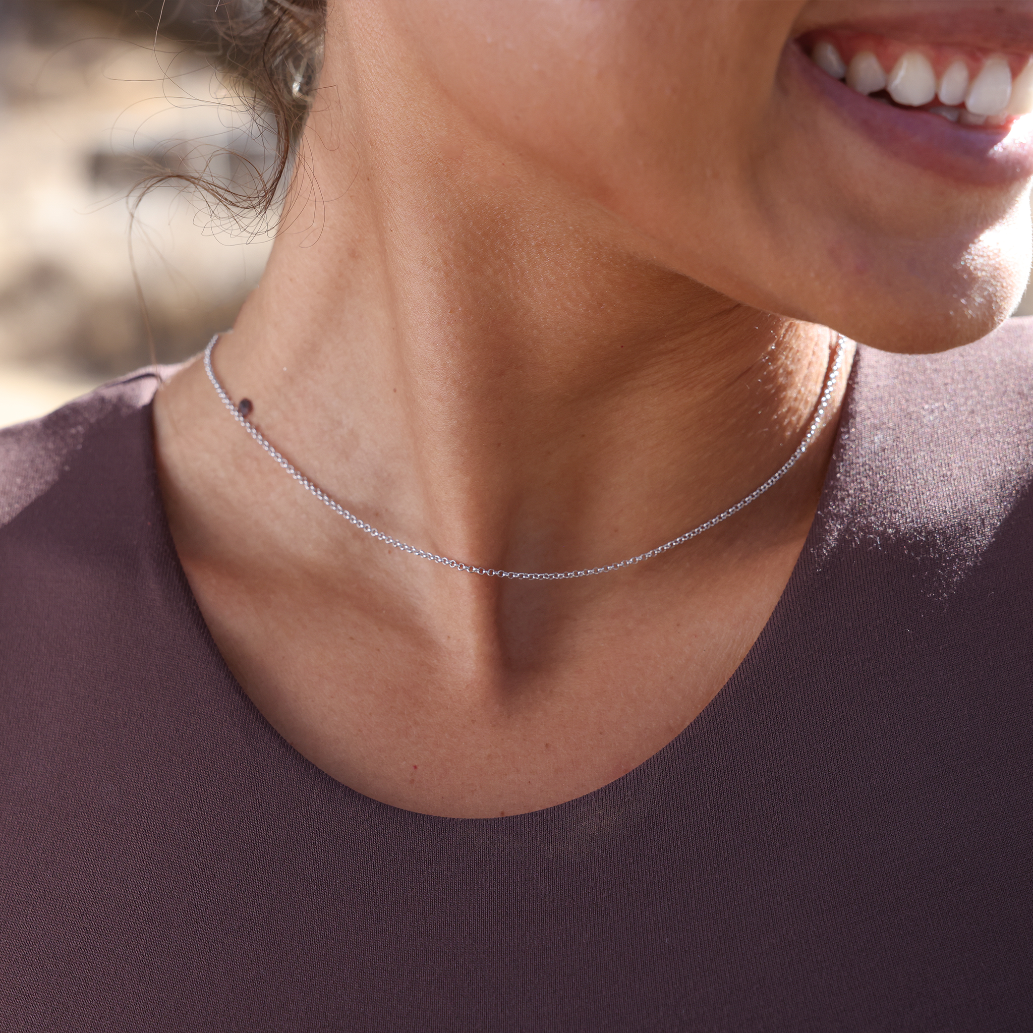 Close up of a woman wearing 1.0mm Rolo Chain in Sterling Silver outdoors