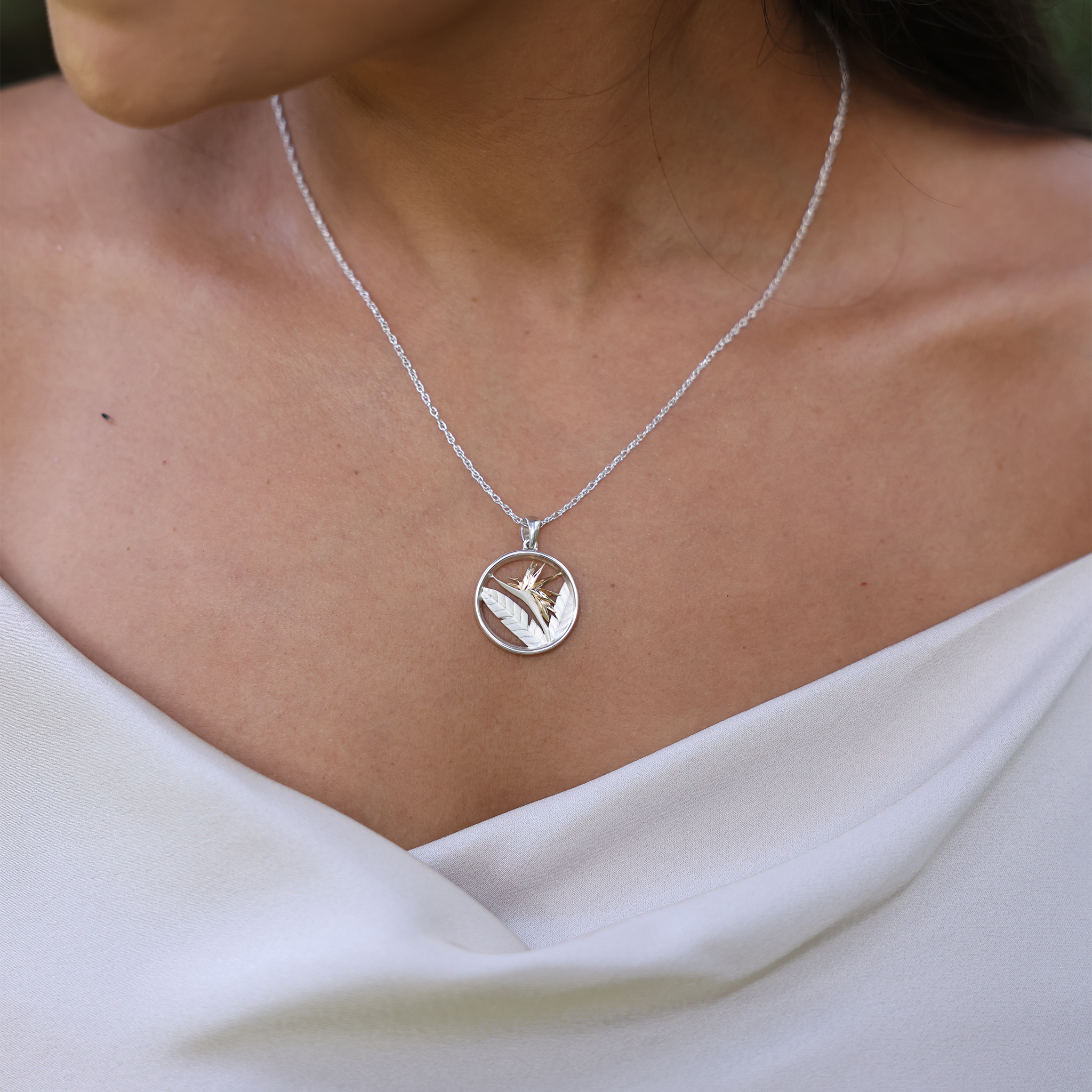 Close up of Birds of Paradise Pendant Necklace in Sterling Silver & Gold on a womanʻs chest