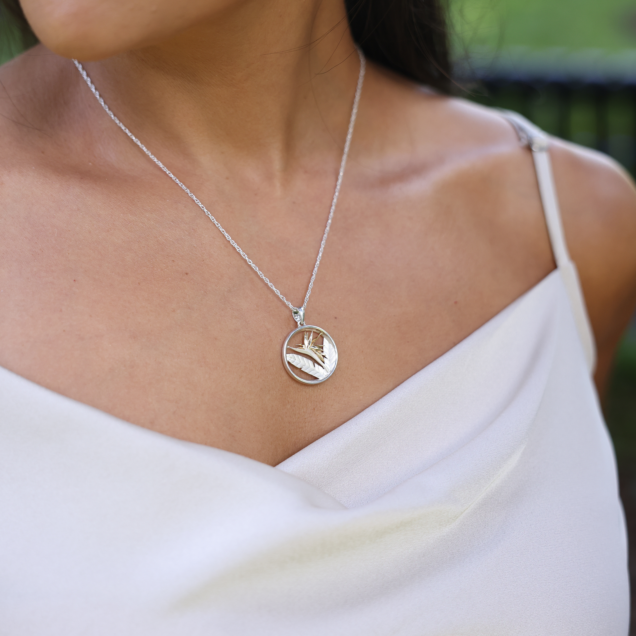 Close up of Birds of Paradise Pendant Necklace in Sterling Silver & Gold on a woman's chest