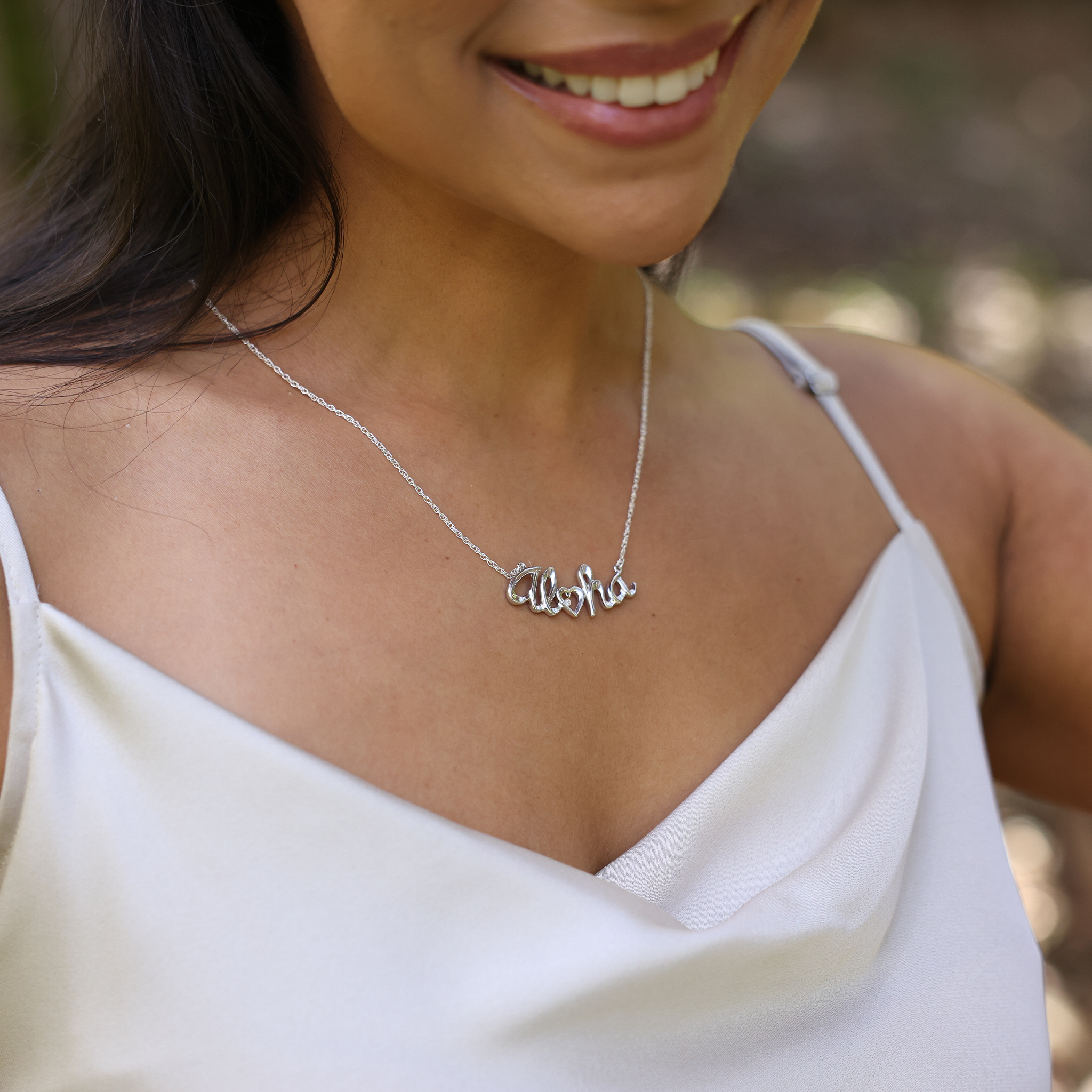 Woman wearing a white top and a Aloha Necklace in Sterling Silver with Diamond bezel set in Gold outdoors