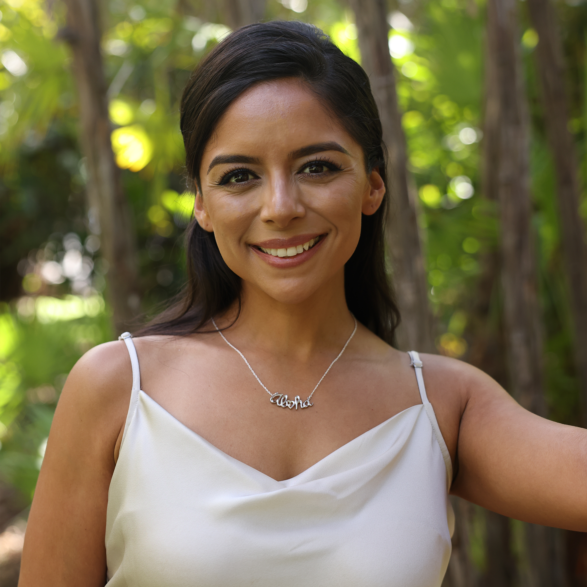 Woman in a garden wearing Aloha Necklace in Sterling Silver with Diamond bezel set in Gold