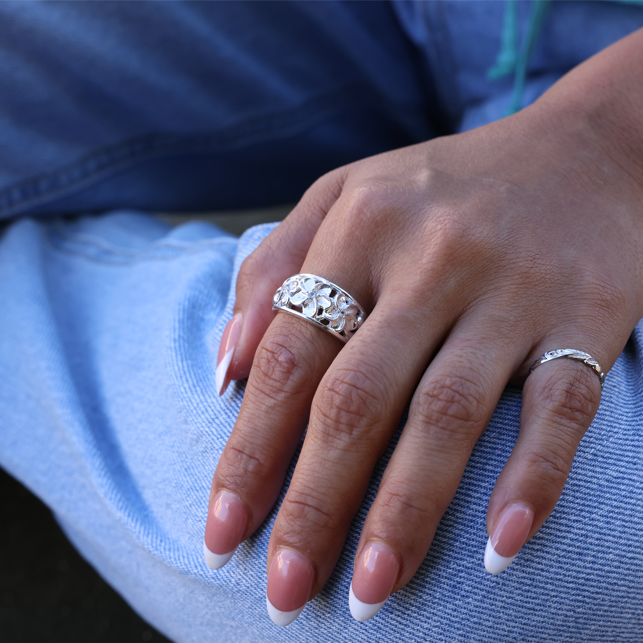 Maui Divers Jewelry Hawaiian Heirloom Plumeria White Sapphire Ring in Sterling Silver on Model Hand touching blue jeans