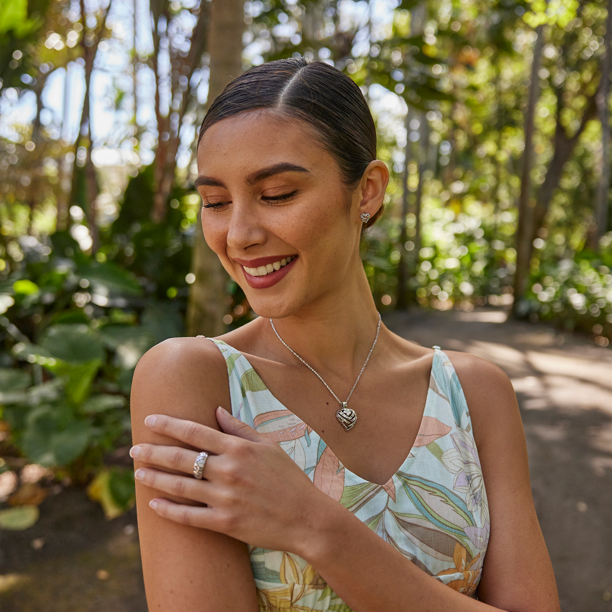 Woman in a garden wearing Aloha Heart Earrings and necklace in Sterling Silver