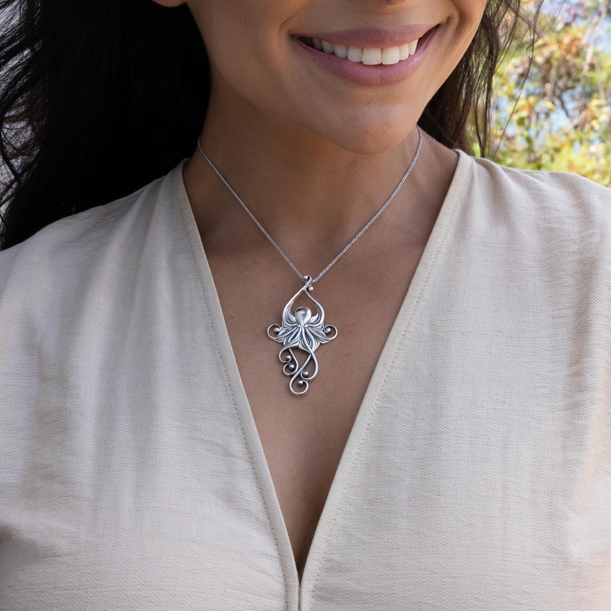 A woman outdoors wearing a Living Heirloom Octopus Pendant in Sterling Silver