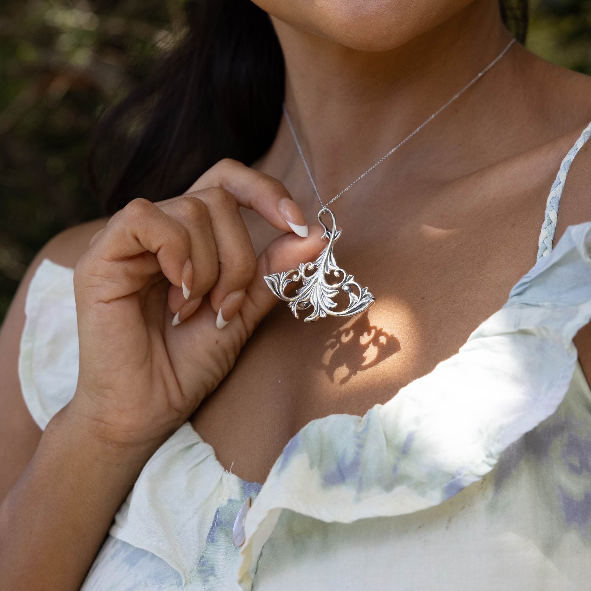 Woman outdoors wearing and holding a Living Heirloom Manta Ray Pendant in Sterling Silver
