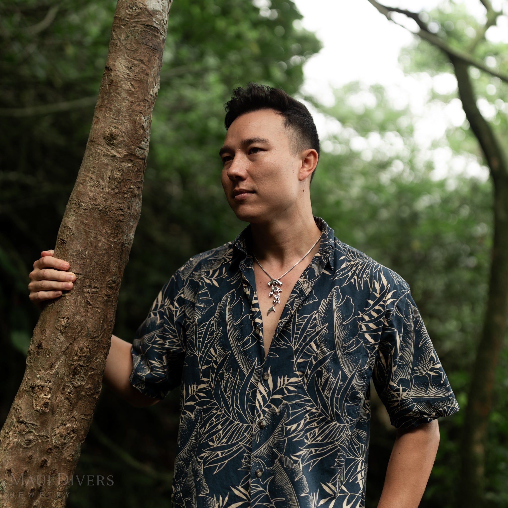 Man in a forest holding a tree and wearing a Living Heirloom Hammerhead Shark Pendant in Sterling Silver
