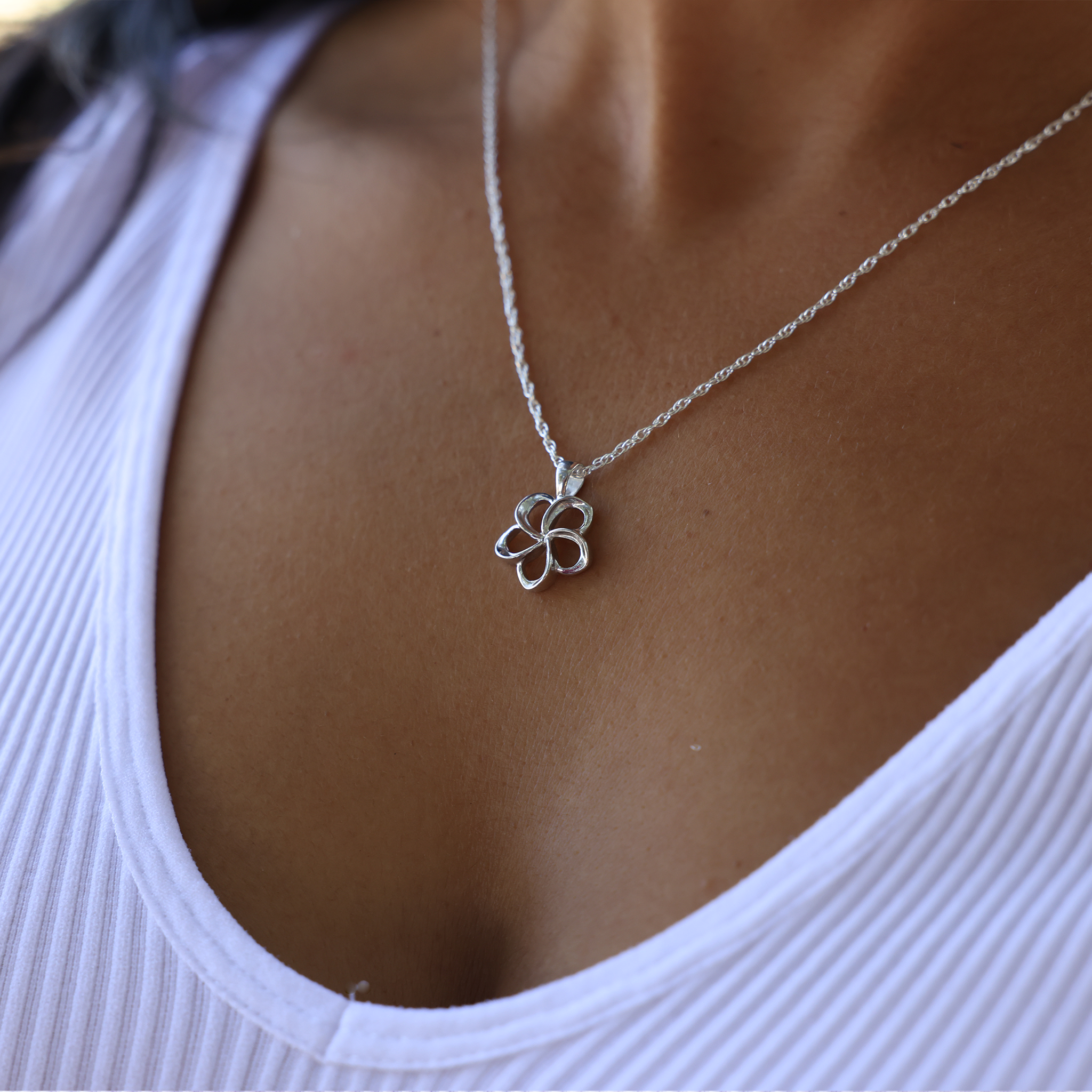 18" Plumeria Pendant in Sterling Silver - 15mm on a woman's chest with white top