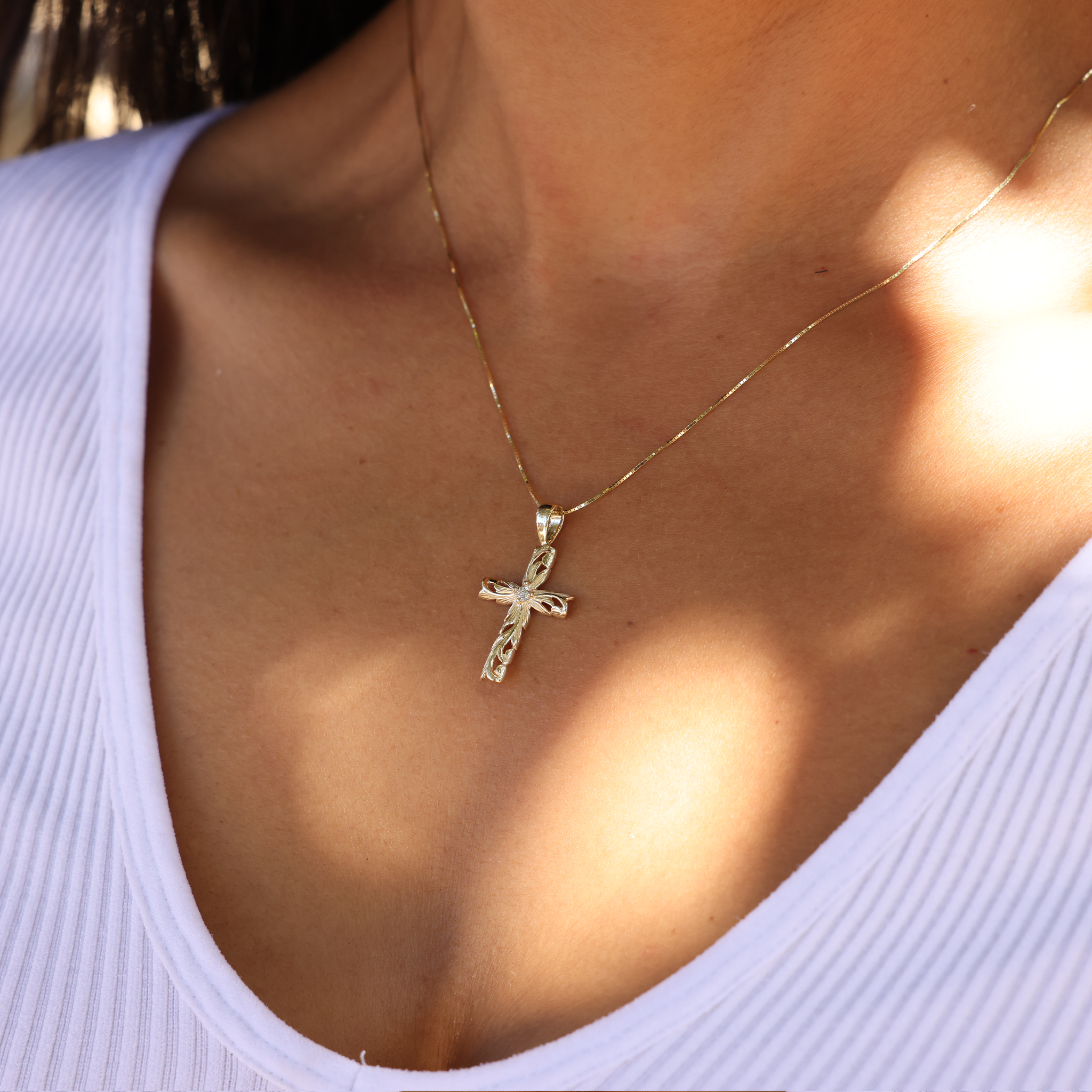 Hawaiian Heirloom Old English Scroll Cross Pendant in Gold with Diamond on Chest just below the necklace with a white shirt