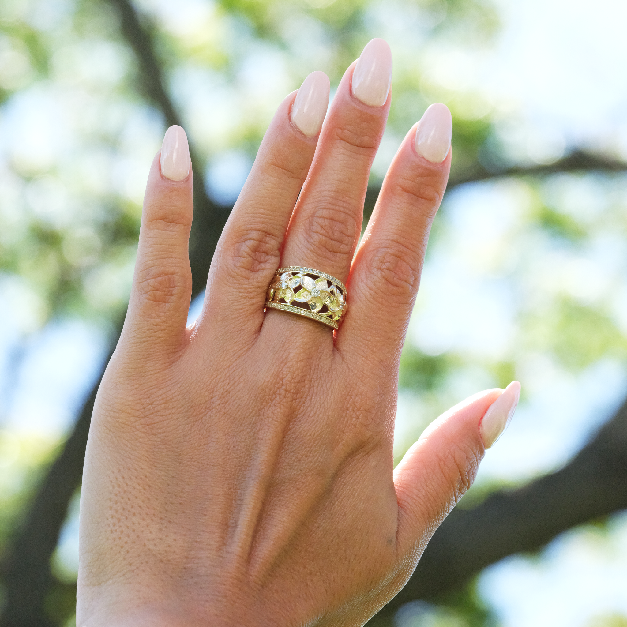 A woman's hand wearing a Hawaiian Heirloom Plumeria Ring in Gold with Diamonds - Maui Divers Jewelry