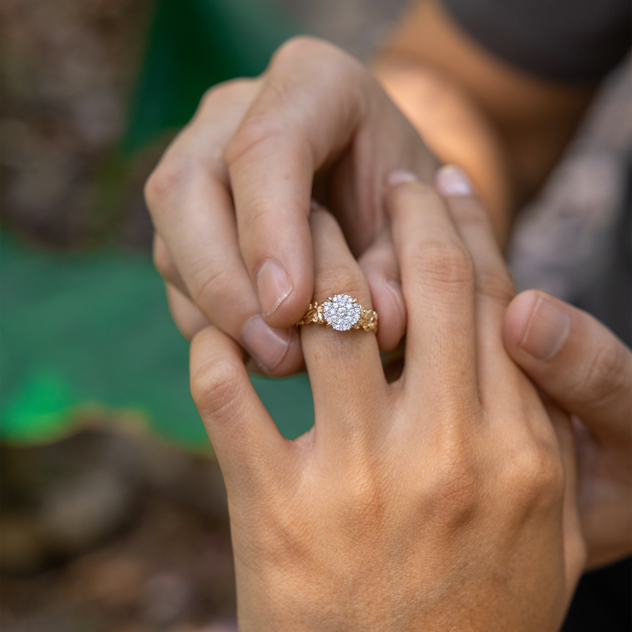 A person's hand placing a Living Heirloom Engagement Ring in Gold with Diamonds on another person's finger
