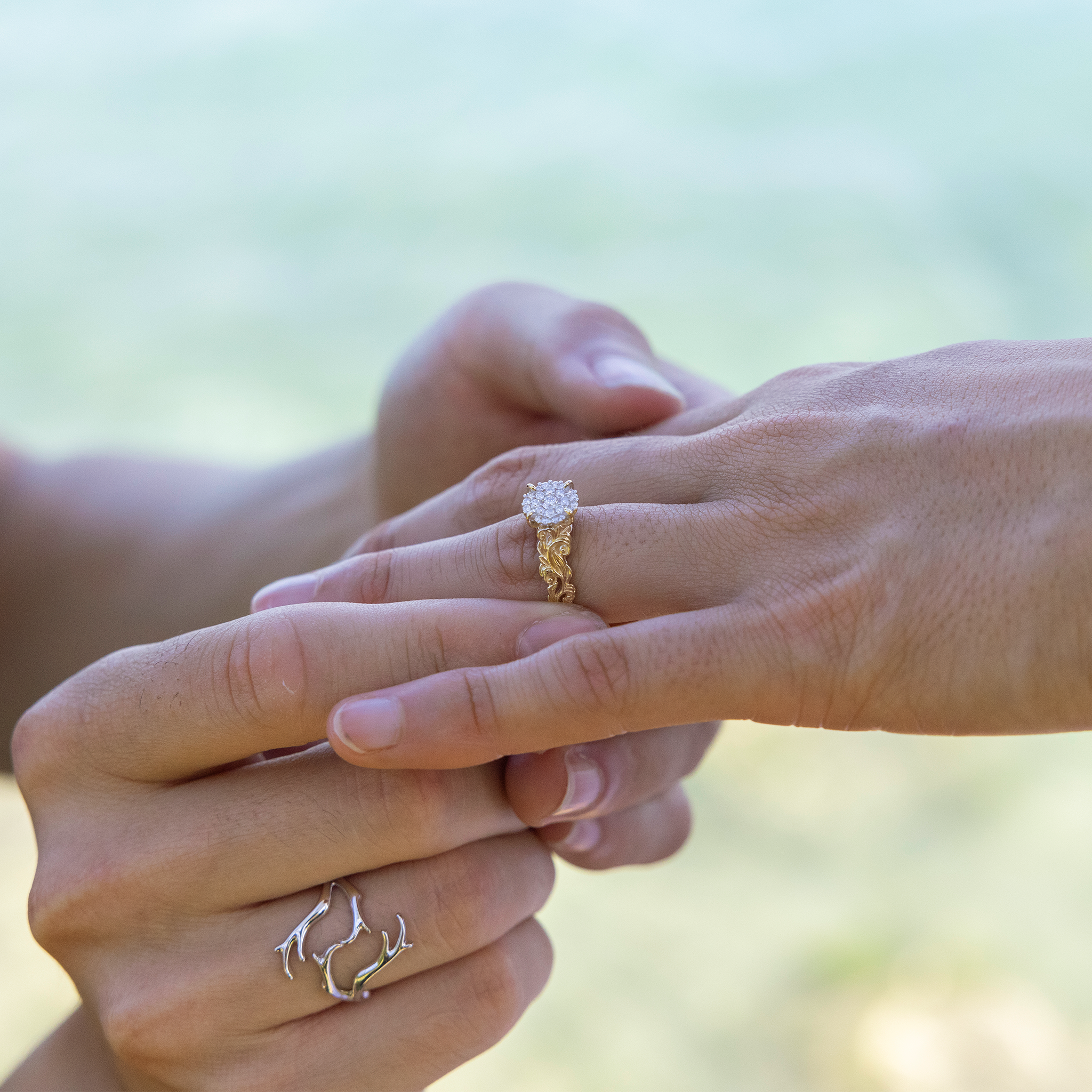 A person placing a Living Heirloom Engagement Ring in Gold with Diamonds on another person's finger