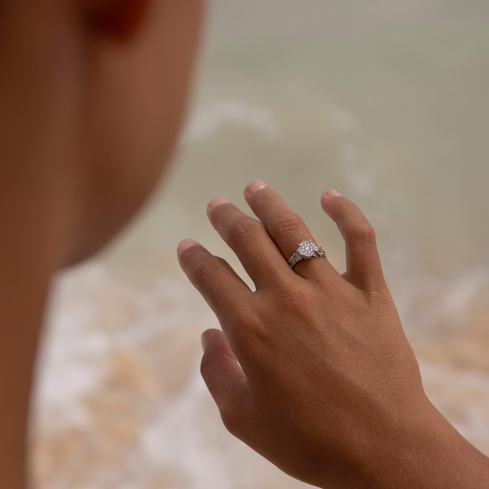 Living Heirloom Engagement Ring in White Gold with Diamonds on a woman with blurred ocean in the back